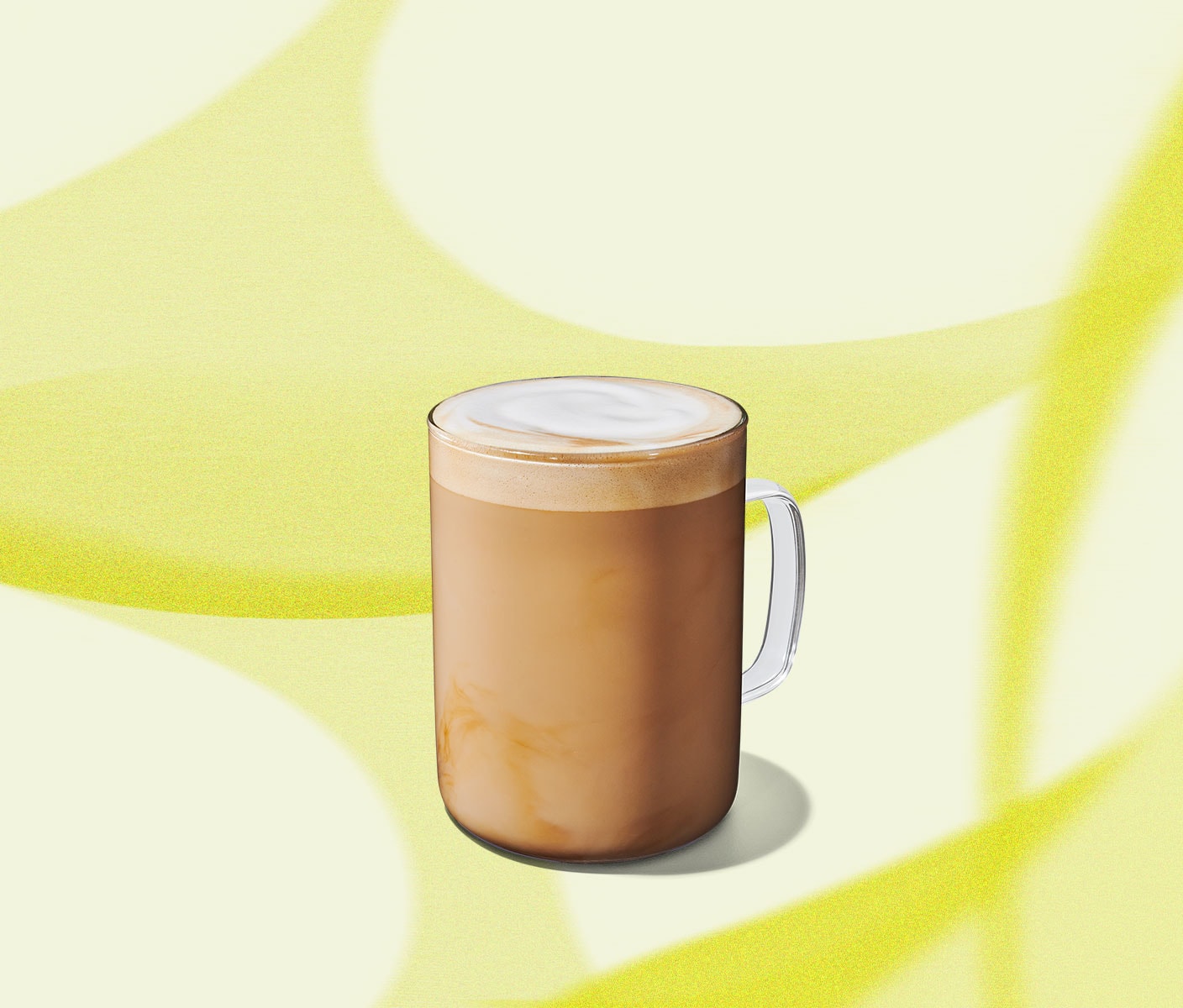 A creamy coffee drink in a clear glass mug with a handle.