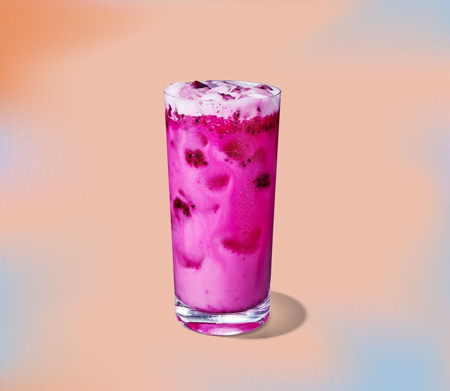 A vibrant-looking drink with real fruit pieces and a frothy top in a tall, clear glass.
