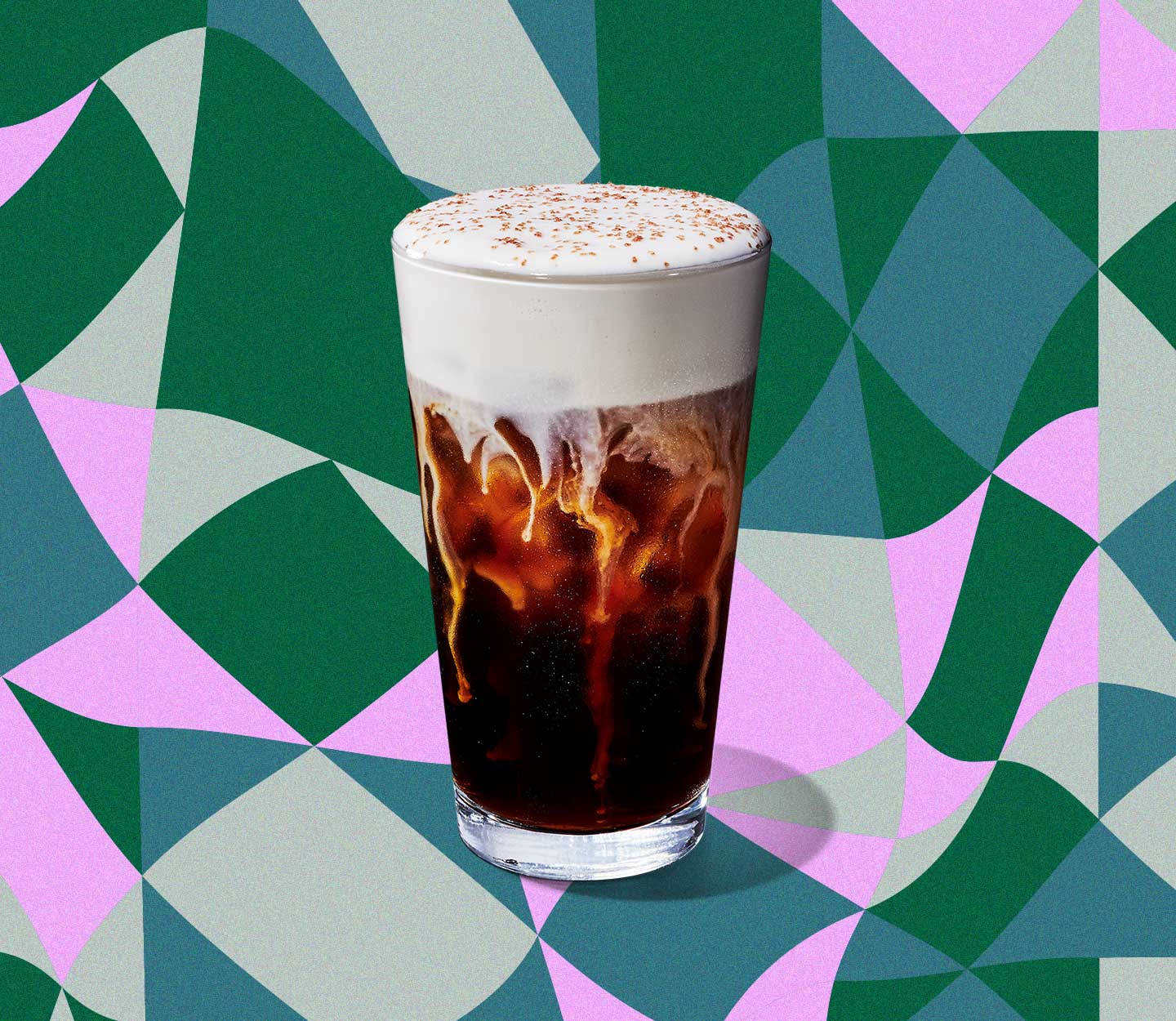 A cold coffee drink in a tall glass with thick foam on top that’s cascading into the beverage.