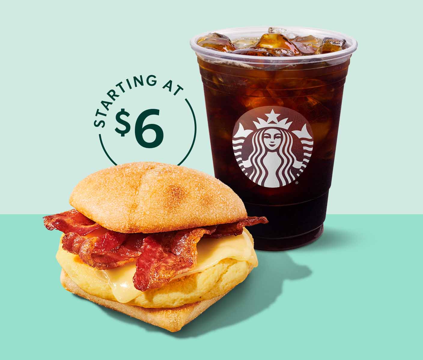 A cup of Starbucks iced coffee sits behind a breakfast sandwich.