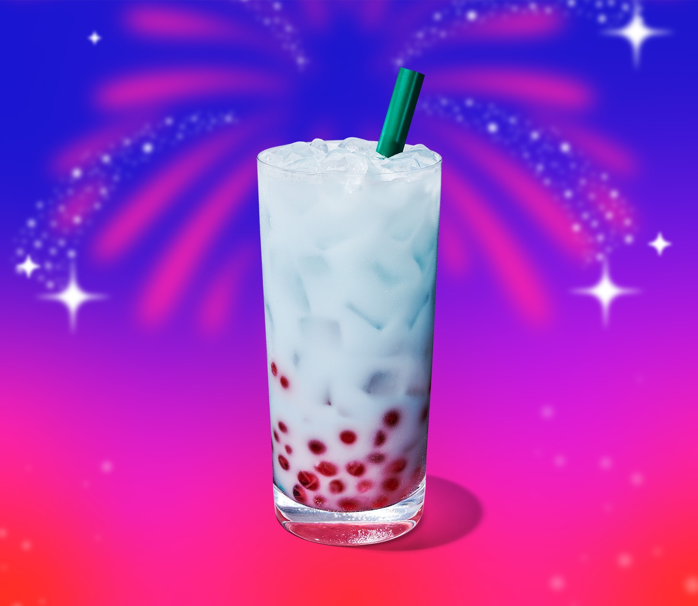 An iced, light blue drink with pink pearls at the bottom of the glass, and fireworks in the background.