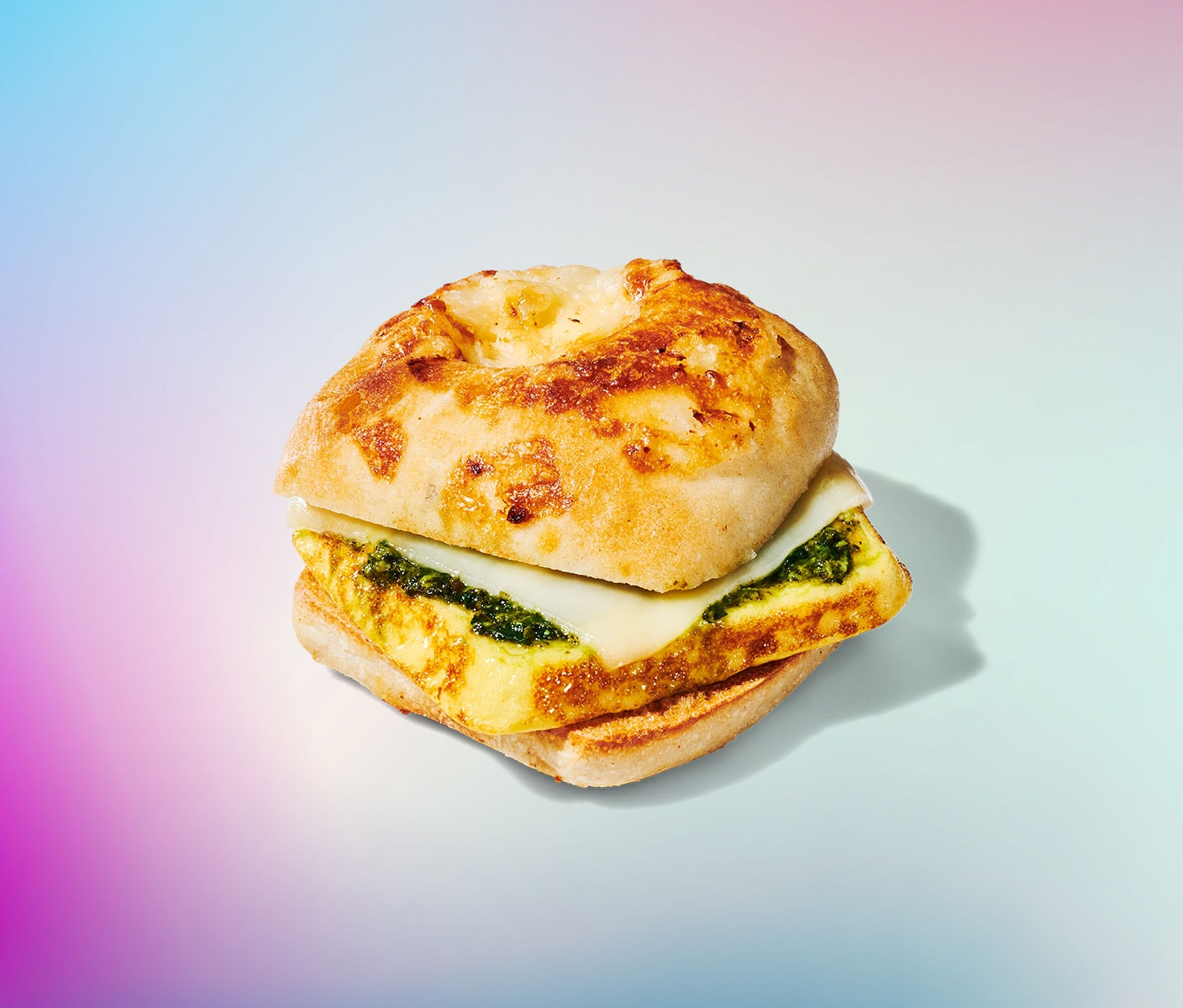 A breakfast sandwich with a fluffy egg frittata and a spread of green pesto sauce.