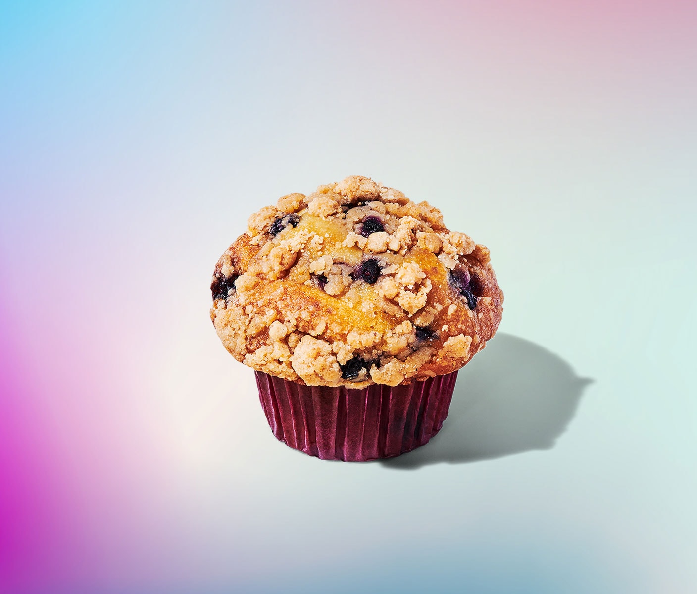 A golden brown muffin with blueberries and a crumbly topping.