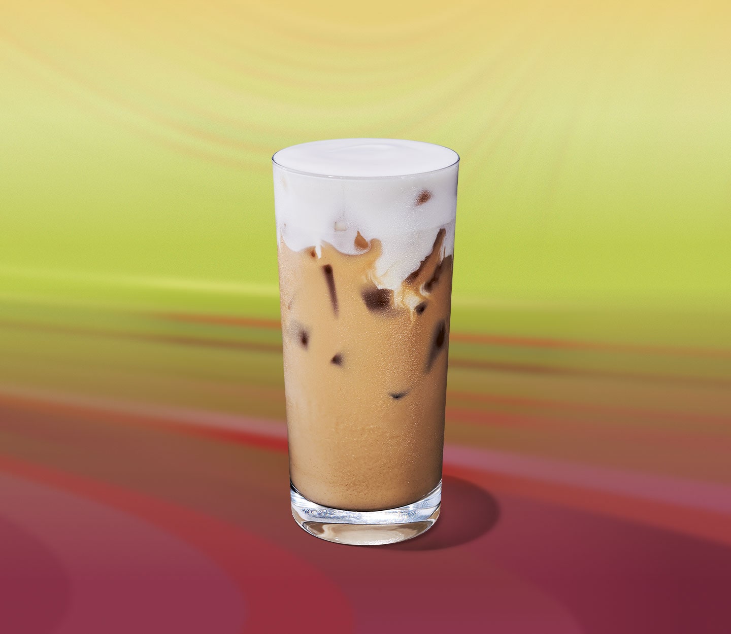 An iced creamy tea drink with a thick, foamy top in a tall glass.