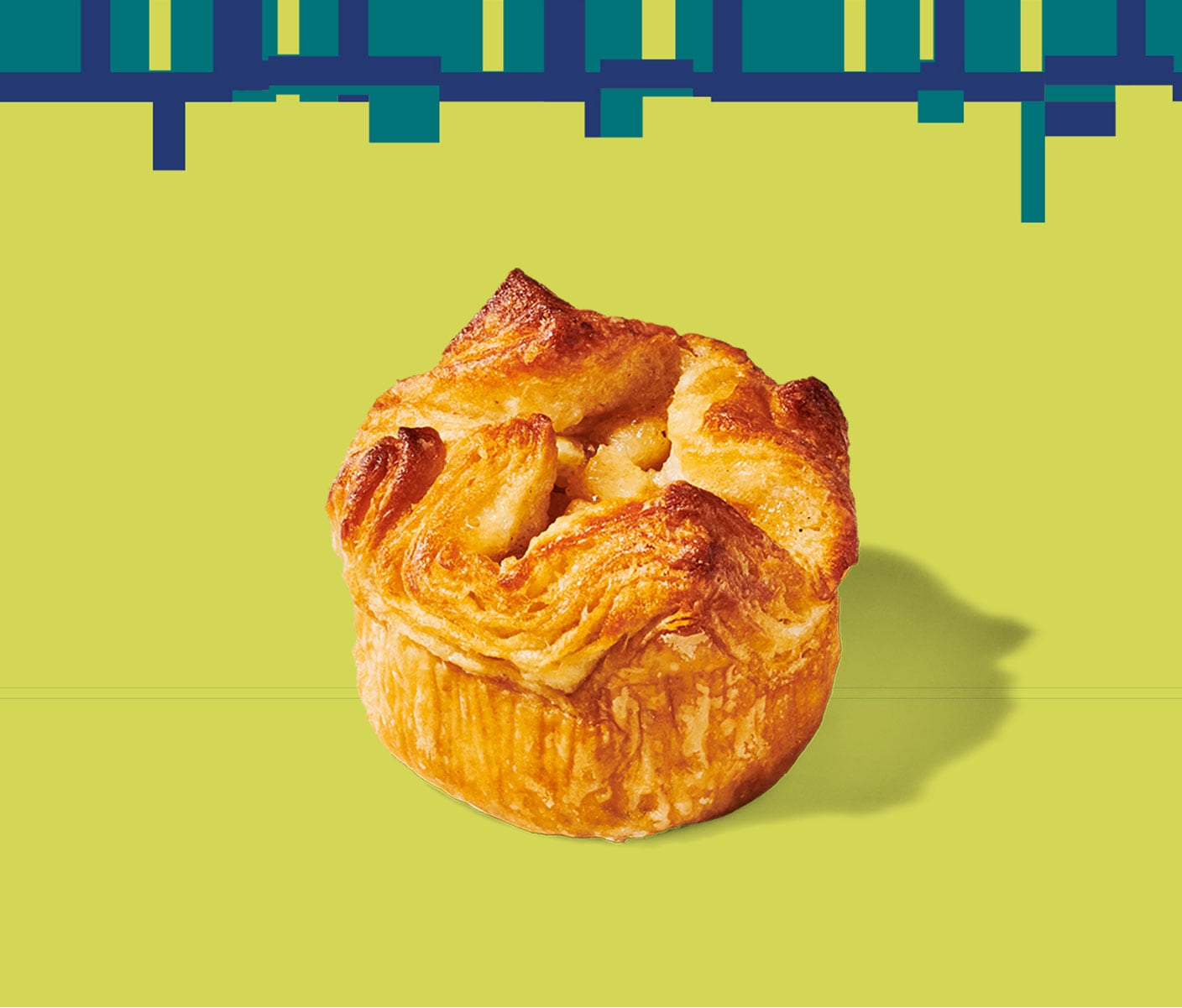 A round, flaky pastry with a wavy texture on top set against a geometric pattern.