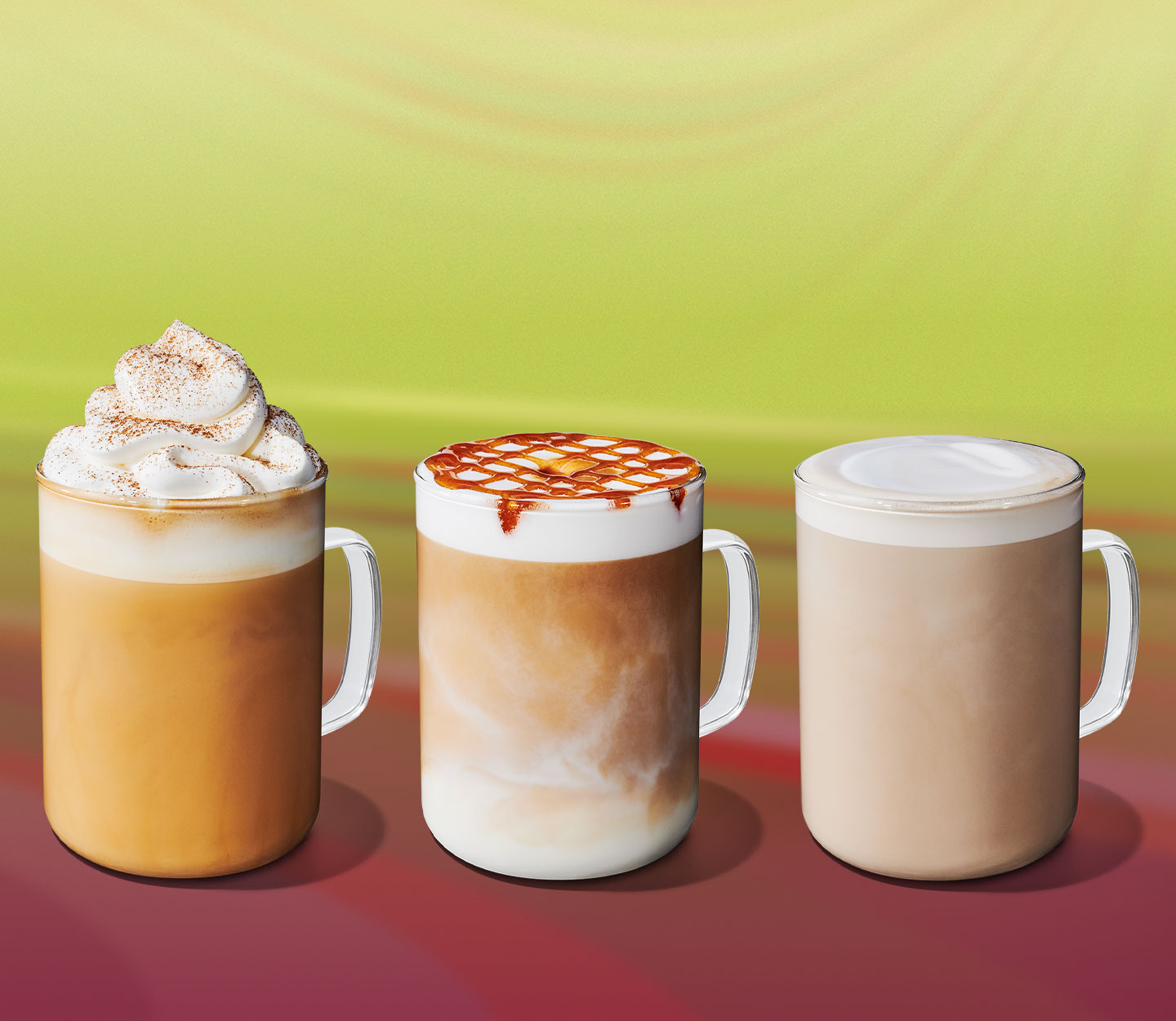 Three hot creamy drinks in mugs: one coffee with whipped cream, one coffee with froth and drizzle, and one tea with a frothy top.