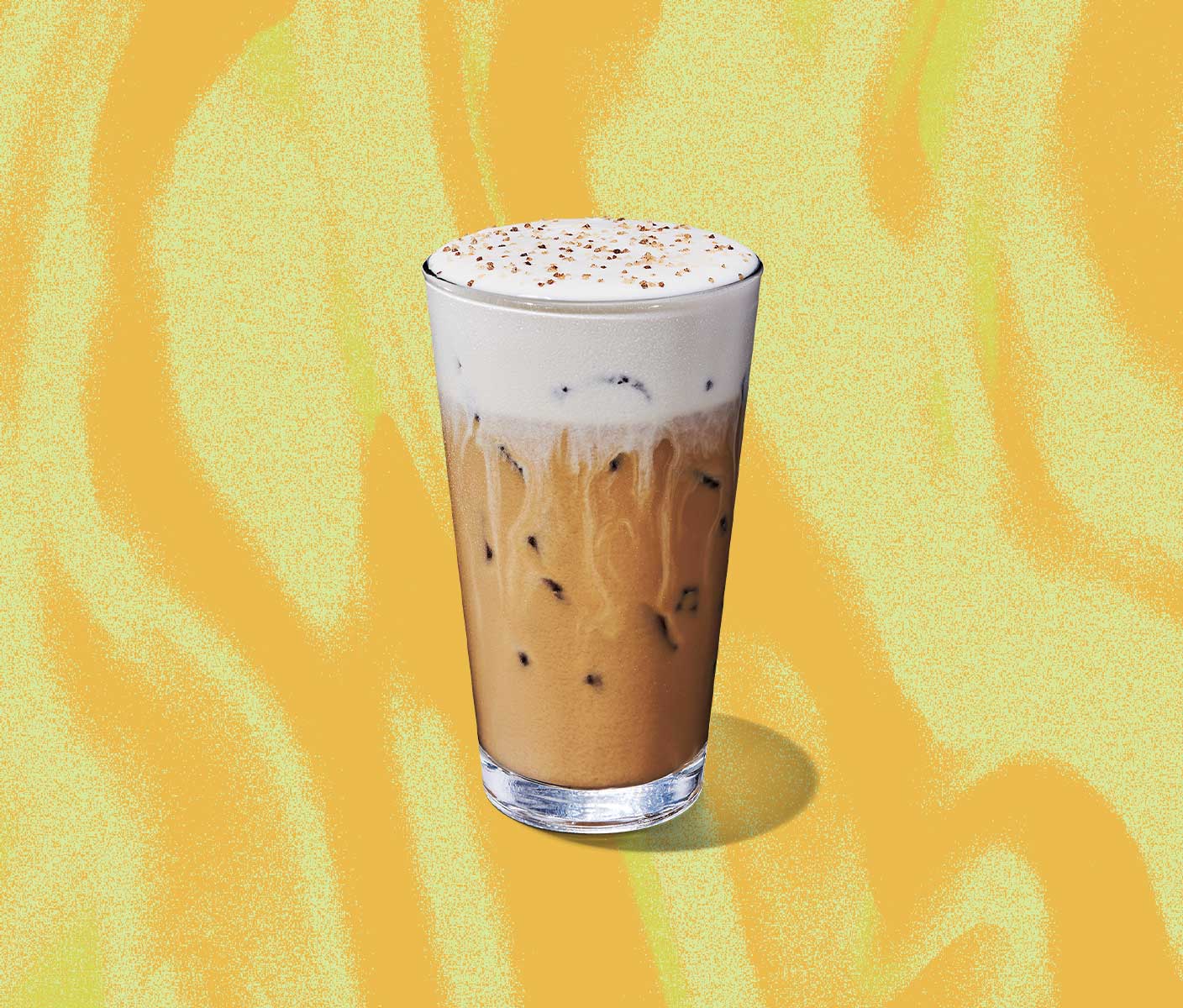 An iced creamy coffee drink with a thick foamy top in a tall glass.