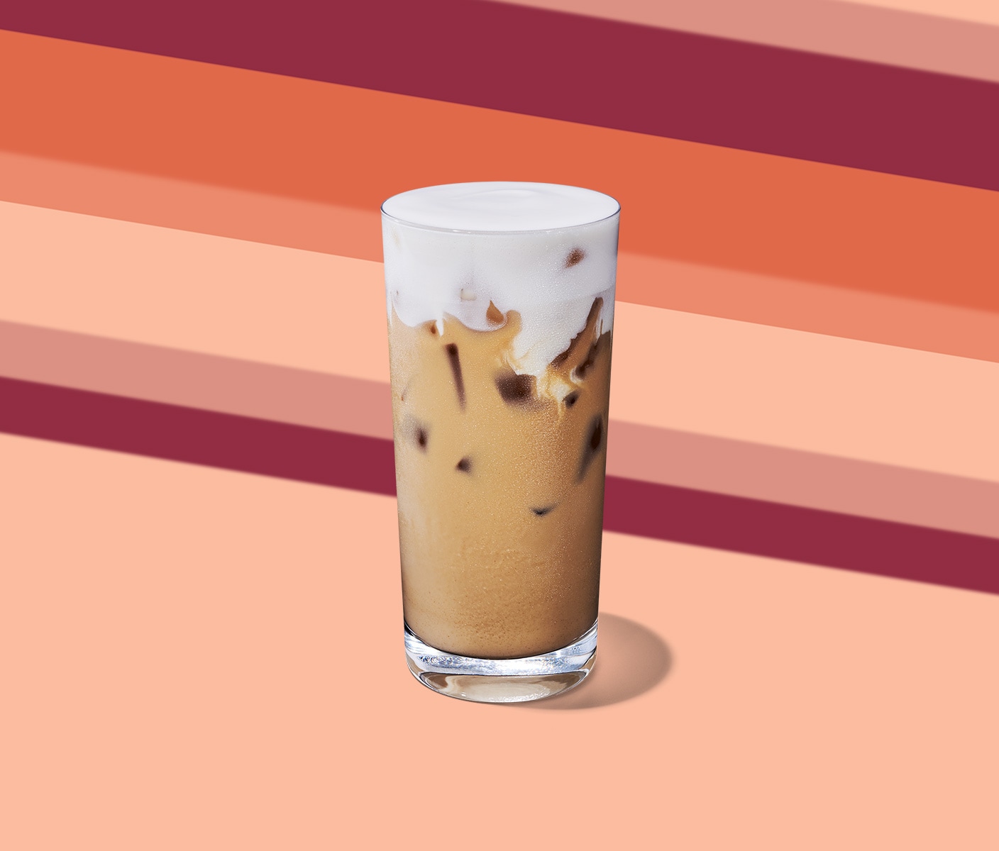 An iced creamy tea drink with a thick, foamy top in a tall glass.