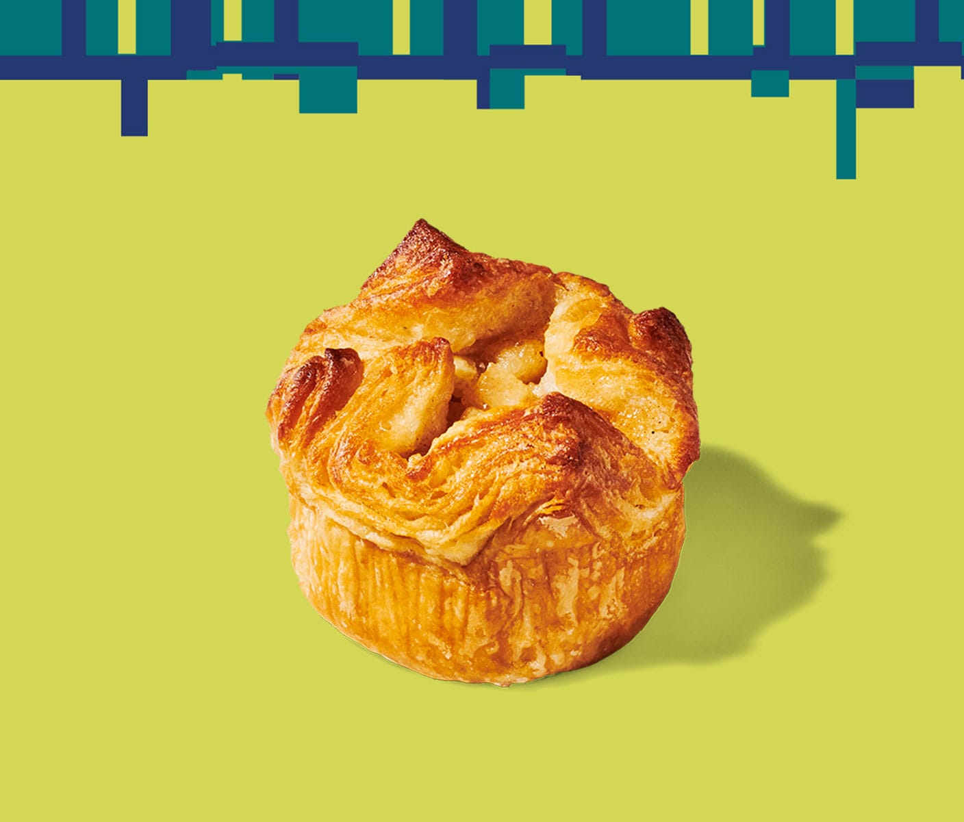 A round, flaky pastry with a wavy texture on top set against a geometric pattern.