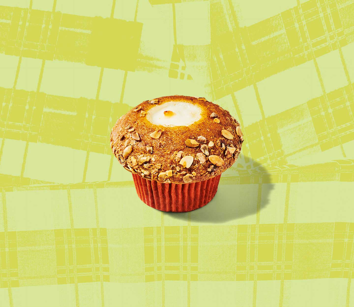 Overhead shot of a round muffin with a nutty topping and cream cheese showing through the top.