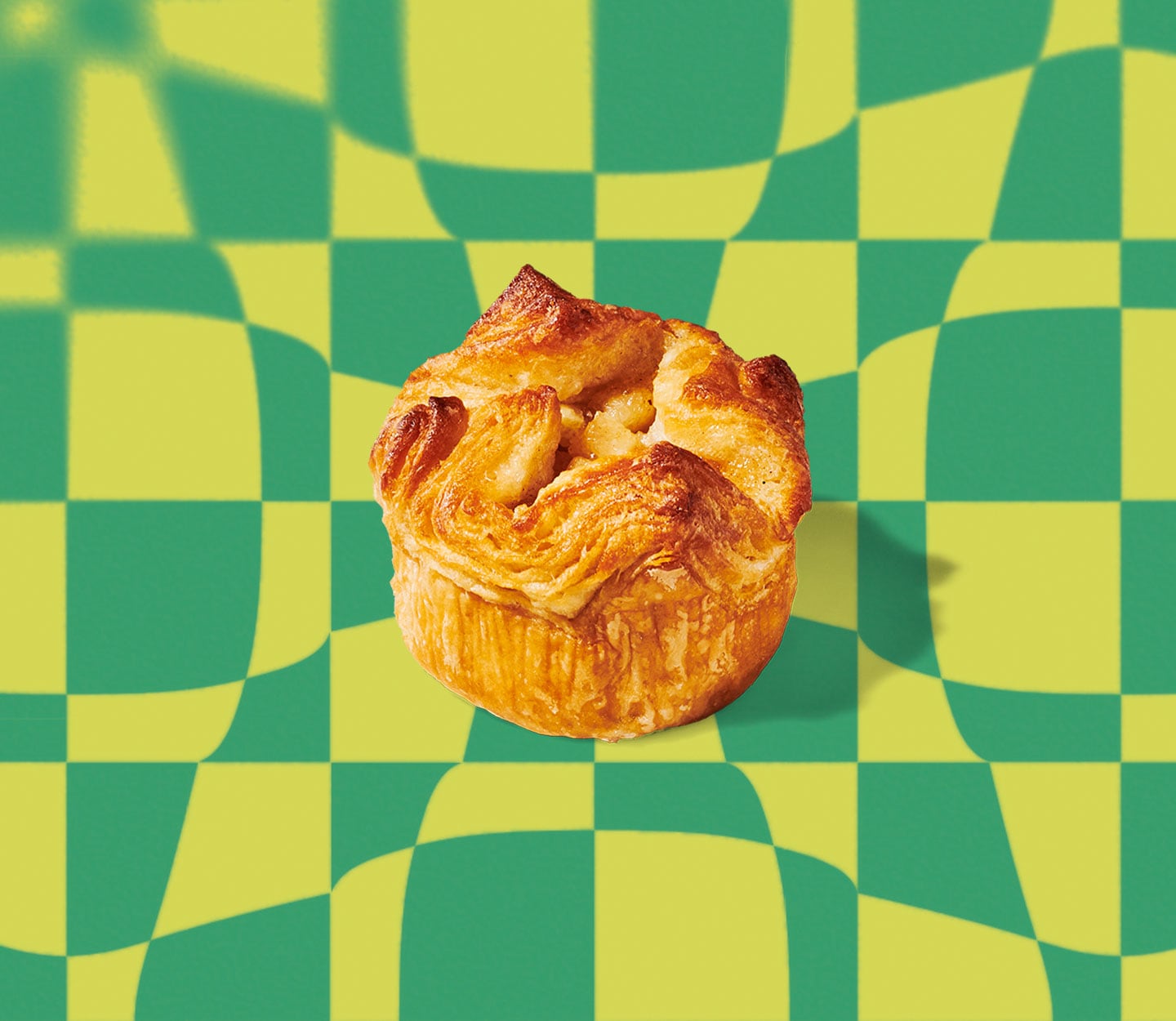 A round, flaky pastry with a wavy texture on top set against a geometric pattern.