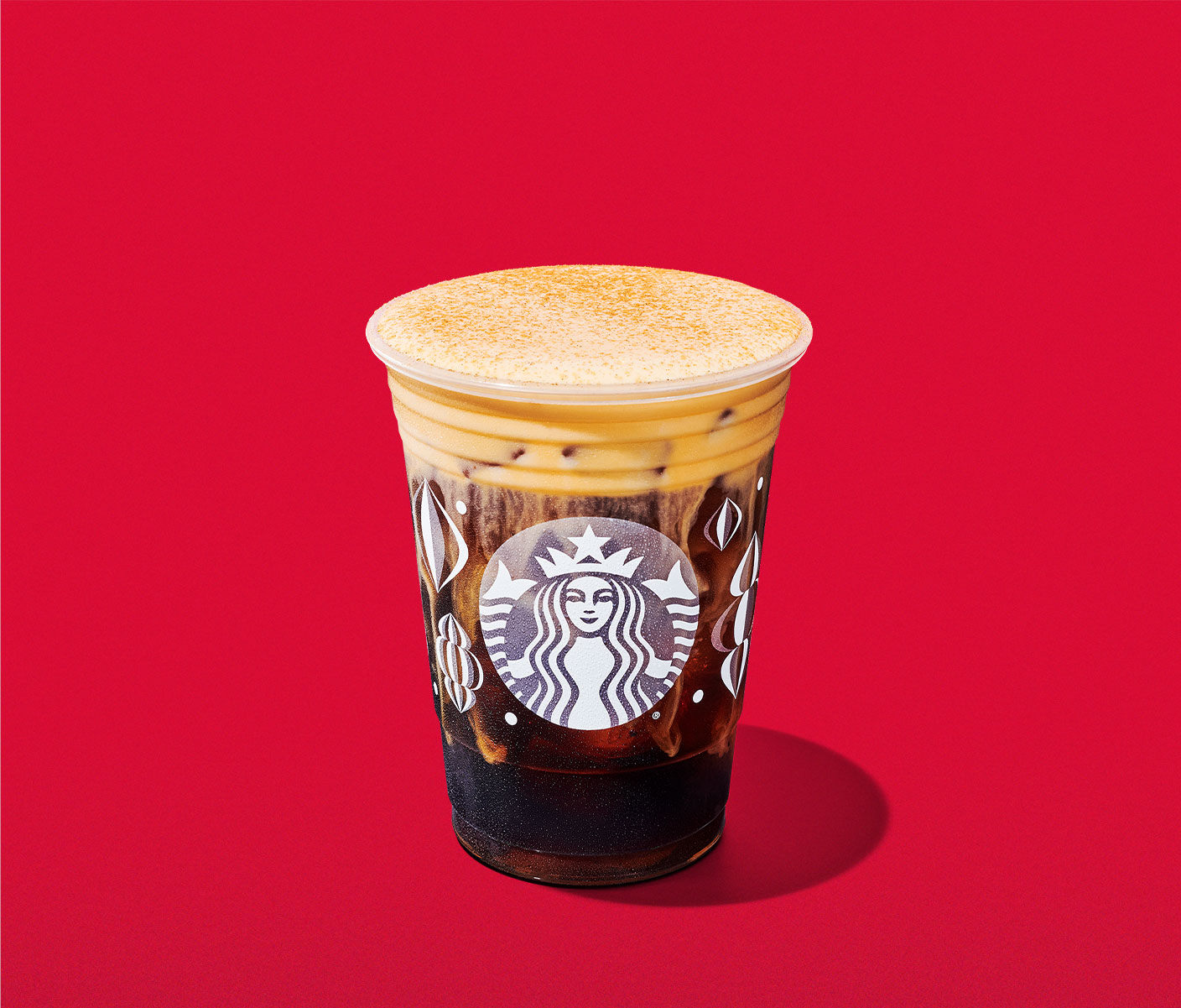 An iced coffee drink with a pumpkin-colored creamy, foamy topping.