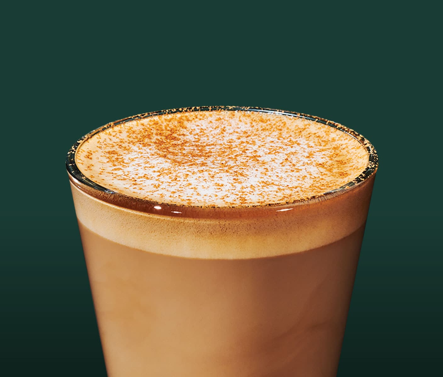 A short-sized creamy coffee drink with a frothy top and light brown sprinkles in a clear glass.