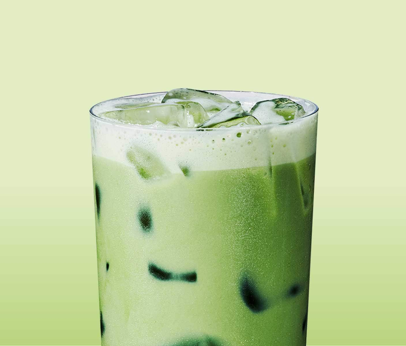 A tall creamy iced green tea drink in a clear narrow glass.