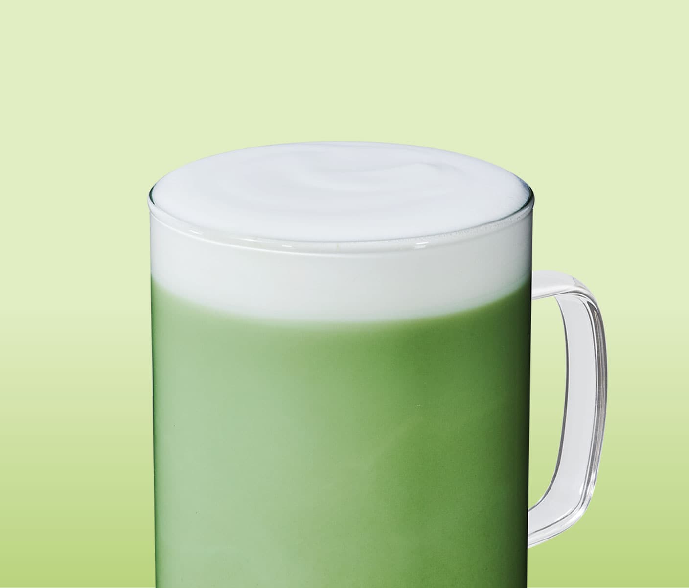 A creamy green tea drink with a frothy top in a clear glass mug.