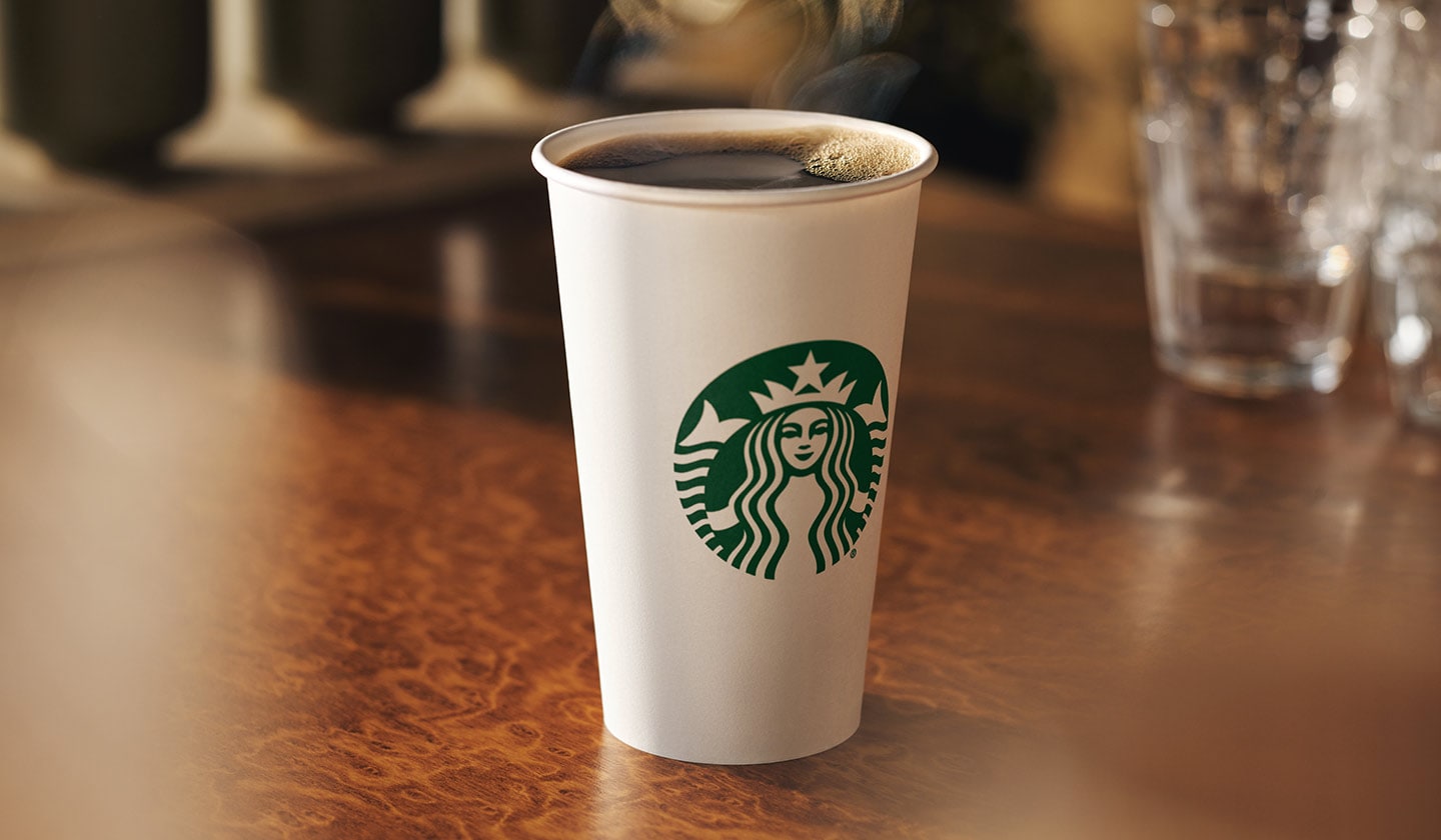 A steaming hot to go cup on a table.