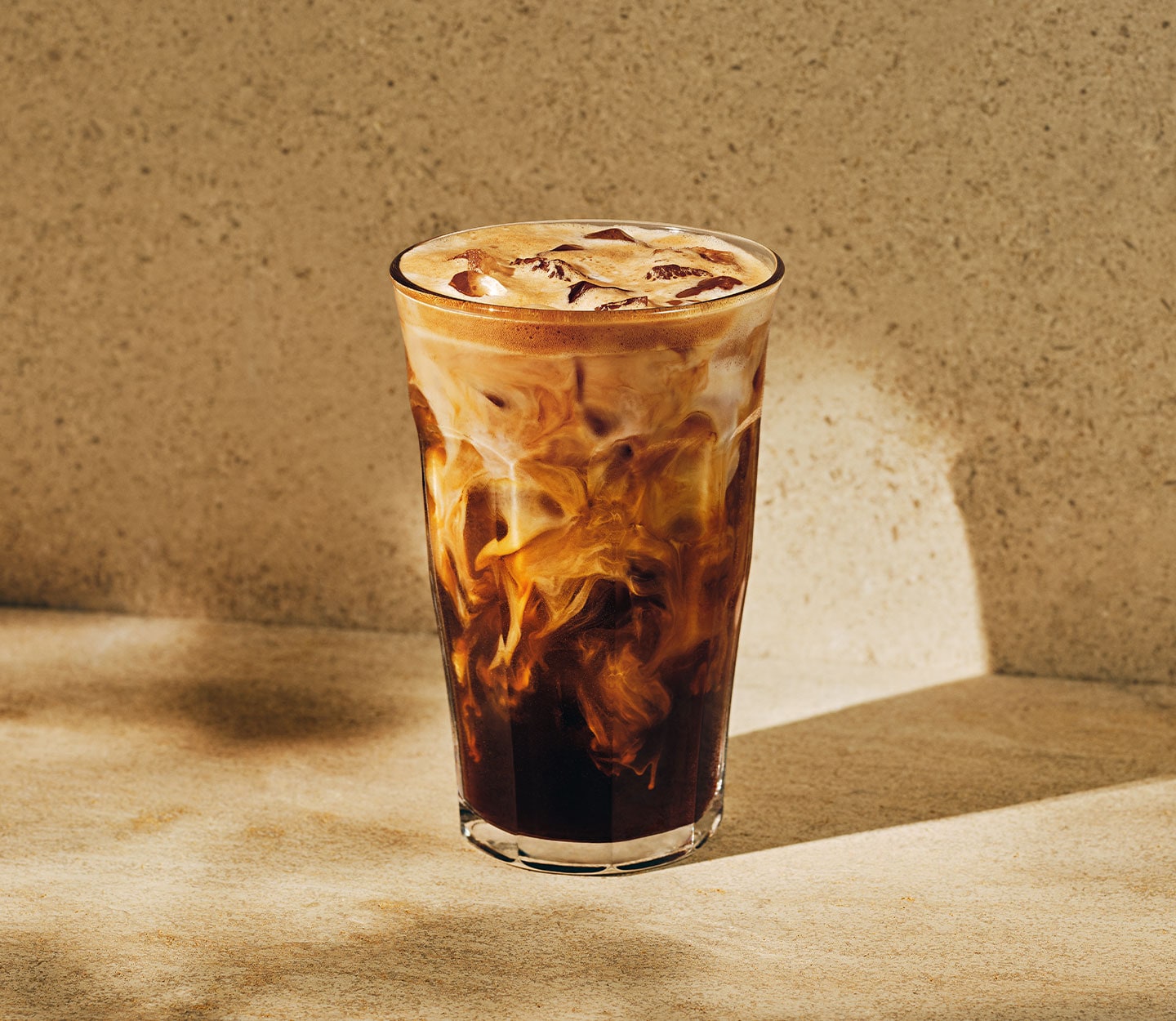 An iced coffee drink in a clear glass with creamy marbling throughout.
