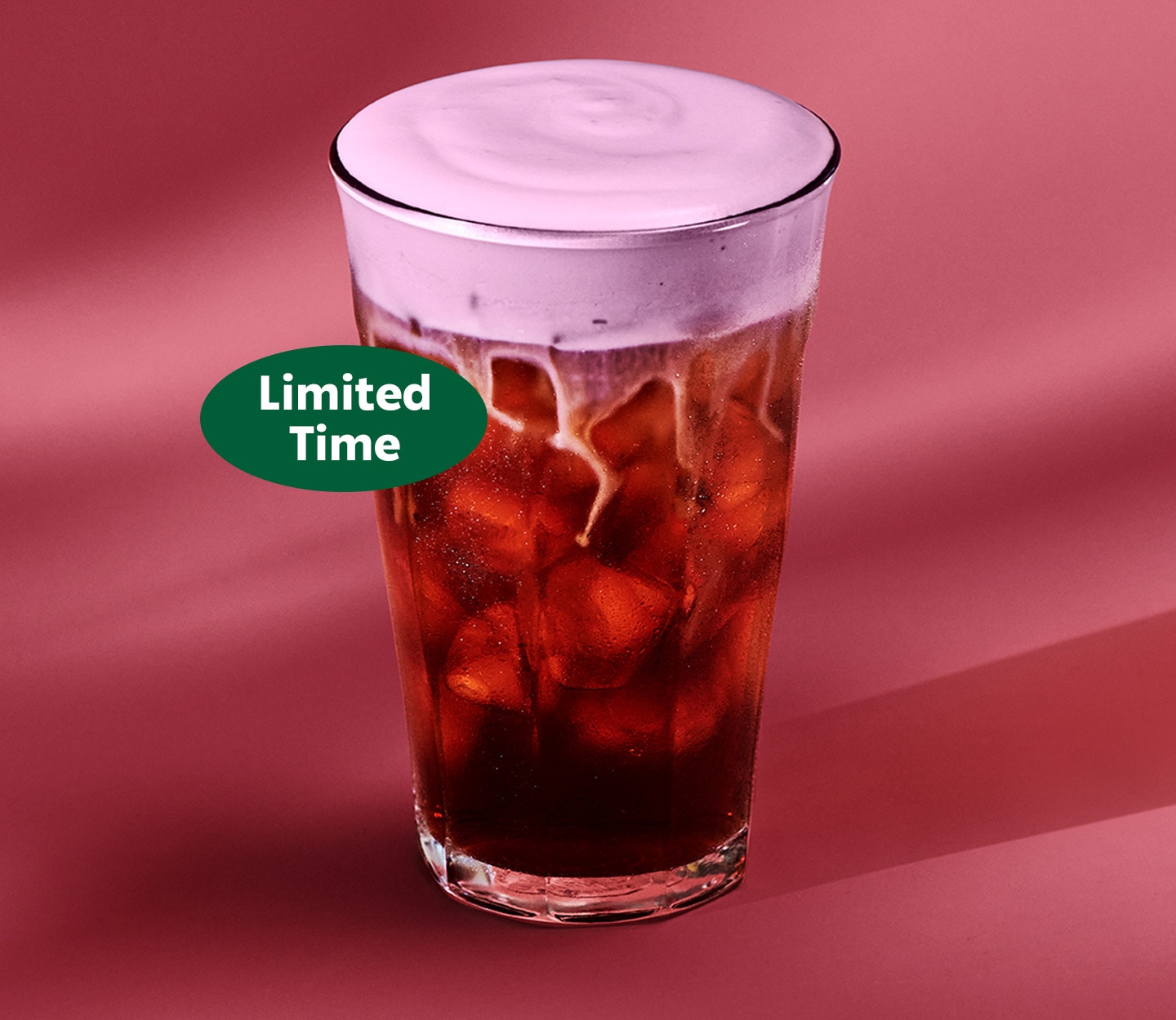 The new Raspberry Cream Cold Brew in a glass cup on a reddish-pink background with a green sticker that reads "Limited Time."