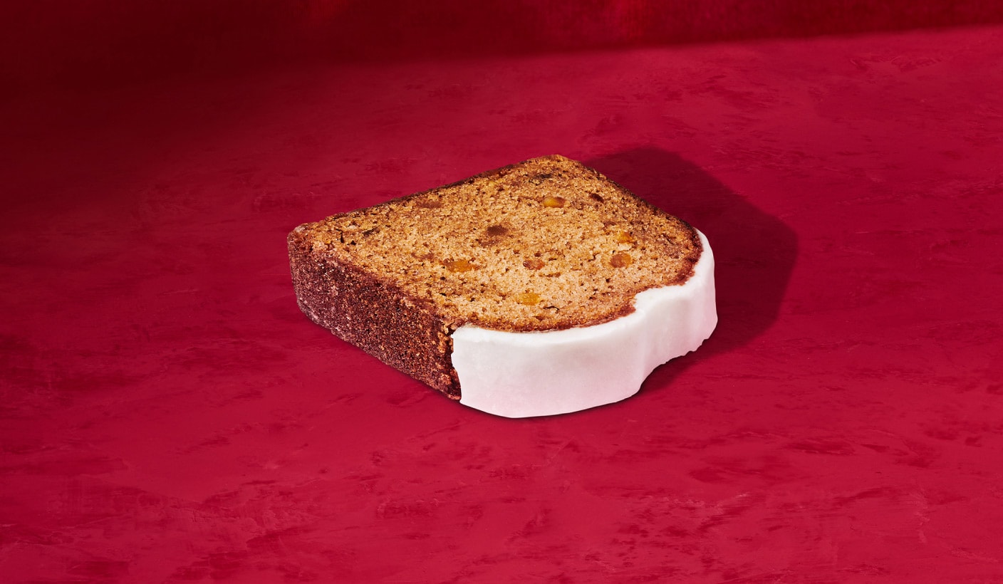 A tasty slice of gingerbread loaf with a sweet layer of icing  on a red background.