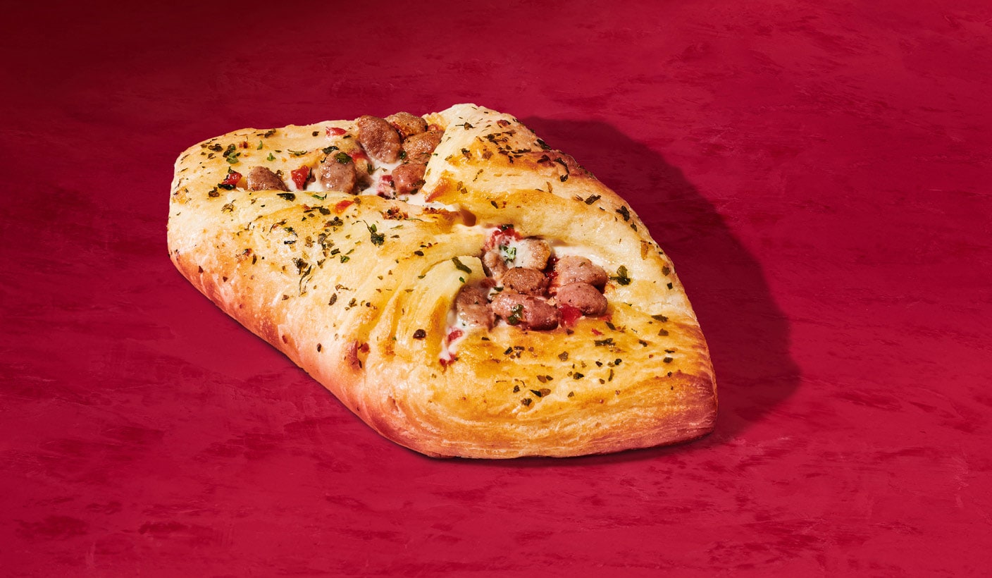 A savoury oven-baked turkey danish sprinkled with sage on a red background.