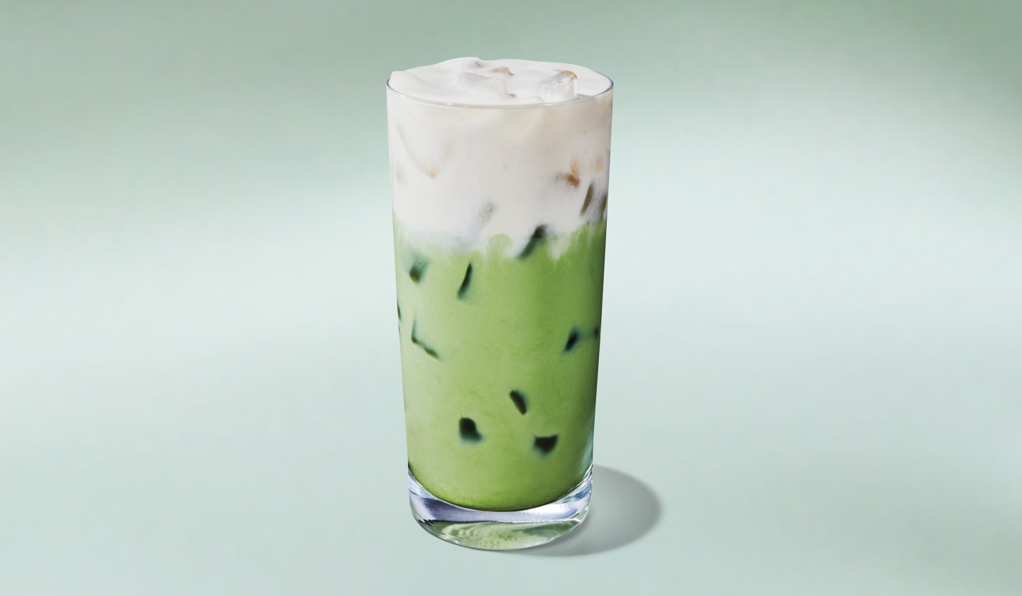 A vibrant green iced matcha topped with fluffy cold foam on a minty green background.