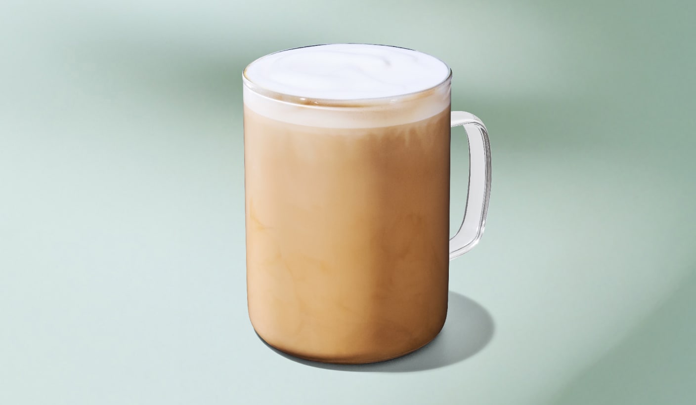 A perfectly steamed latte with a layer of protein milk foam on a minty green background.