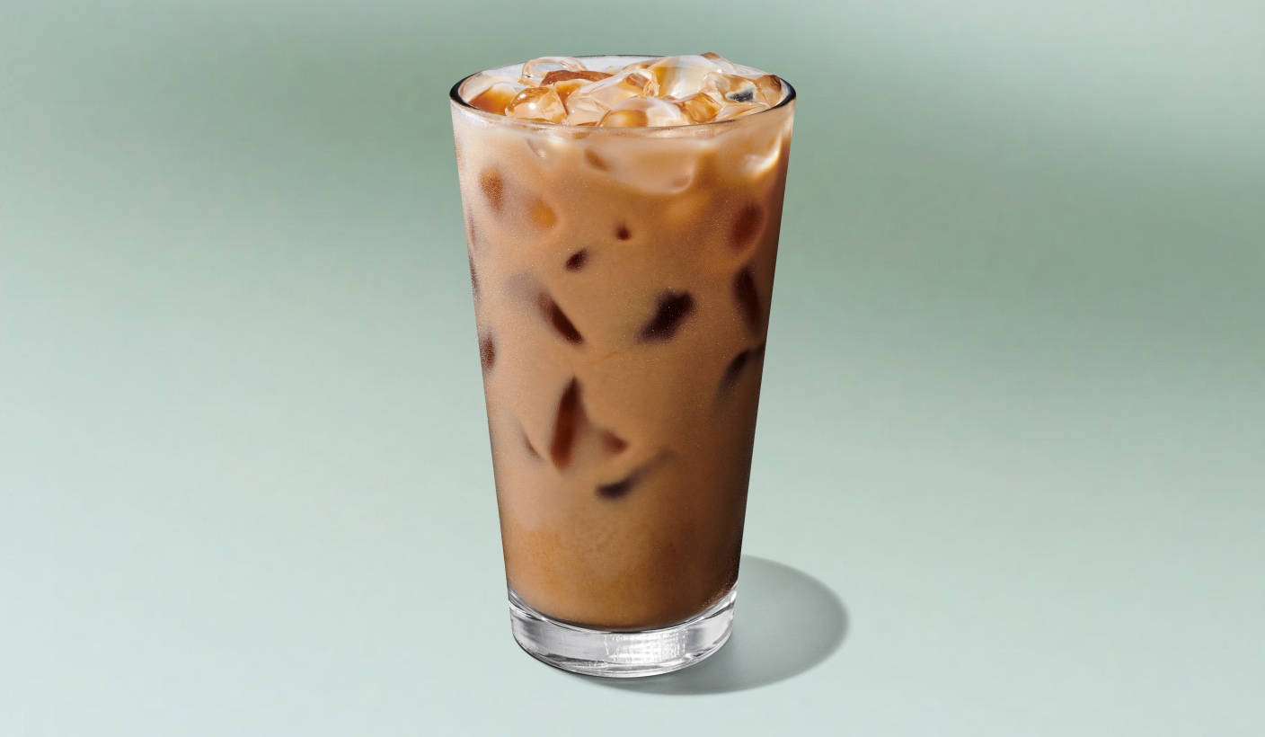 A refreshing iced latte in a tall glass against a minty green background.