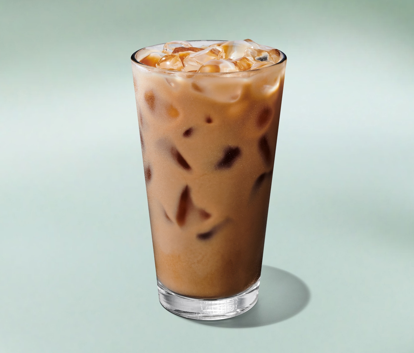 A refreshing Iced Latte in a tall glass against a minty green background.