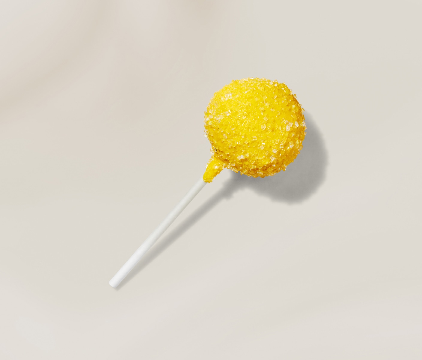 Lemon flavoured cake pop with bright yellow coating and citrus topping, shown against a clean background.