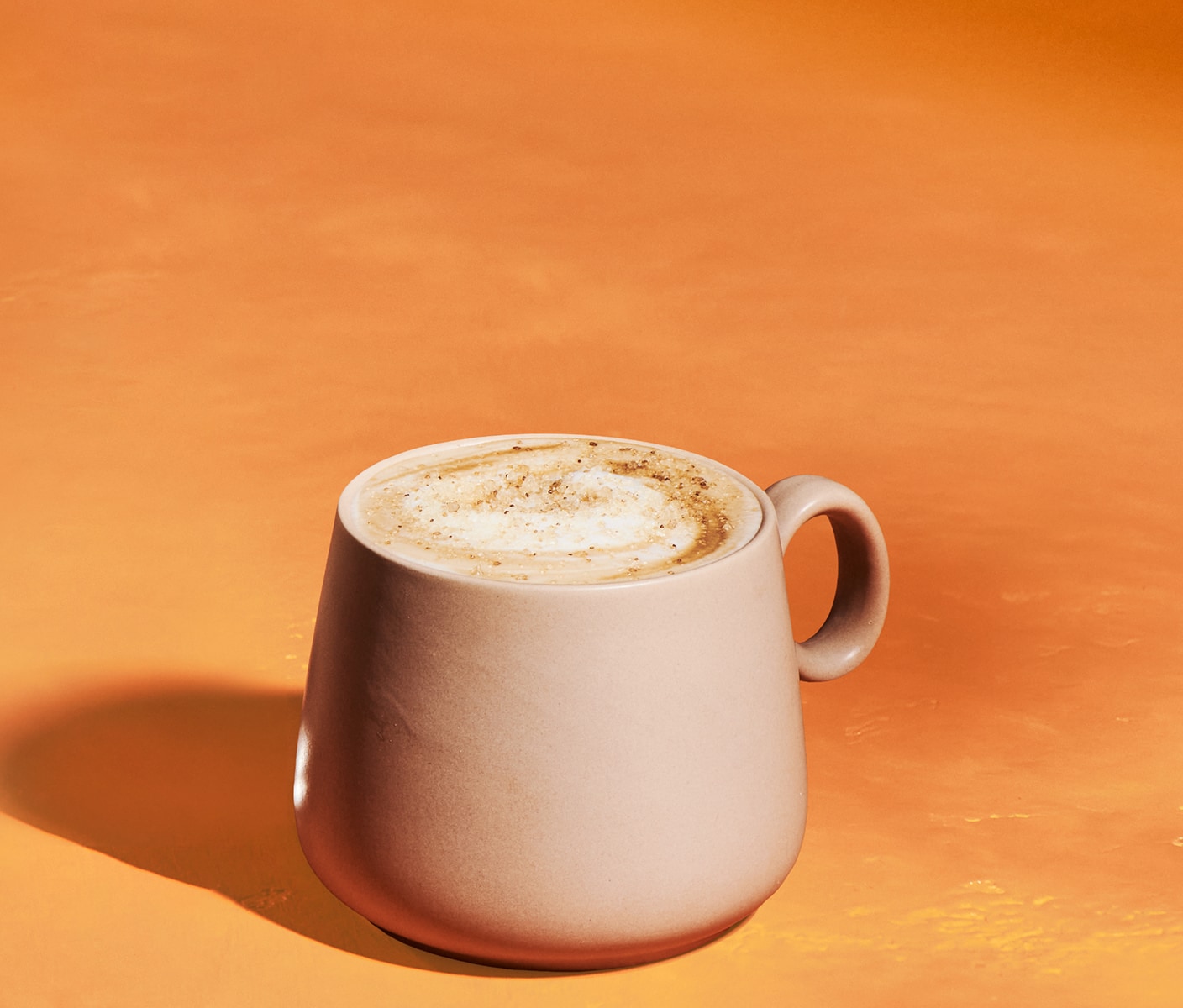 A latte sprinkled with topping in a mug.