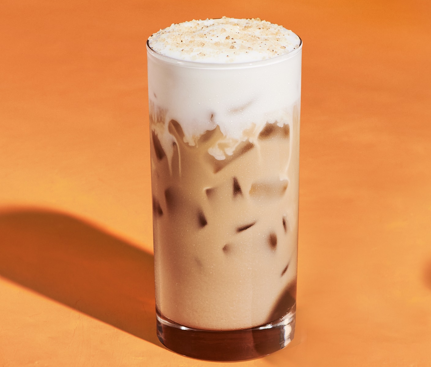 A milky iced coffee with vanilla sweet cream cold foam sprinkled with topping.