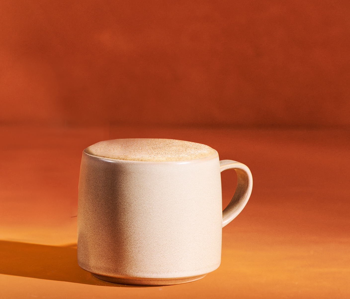 A foamy latte sprinkled with topping in a mug.