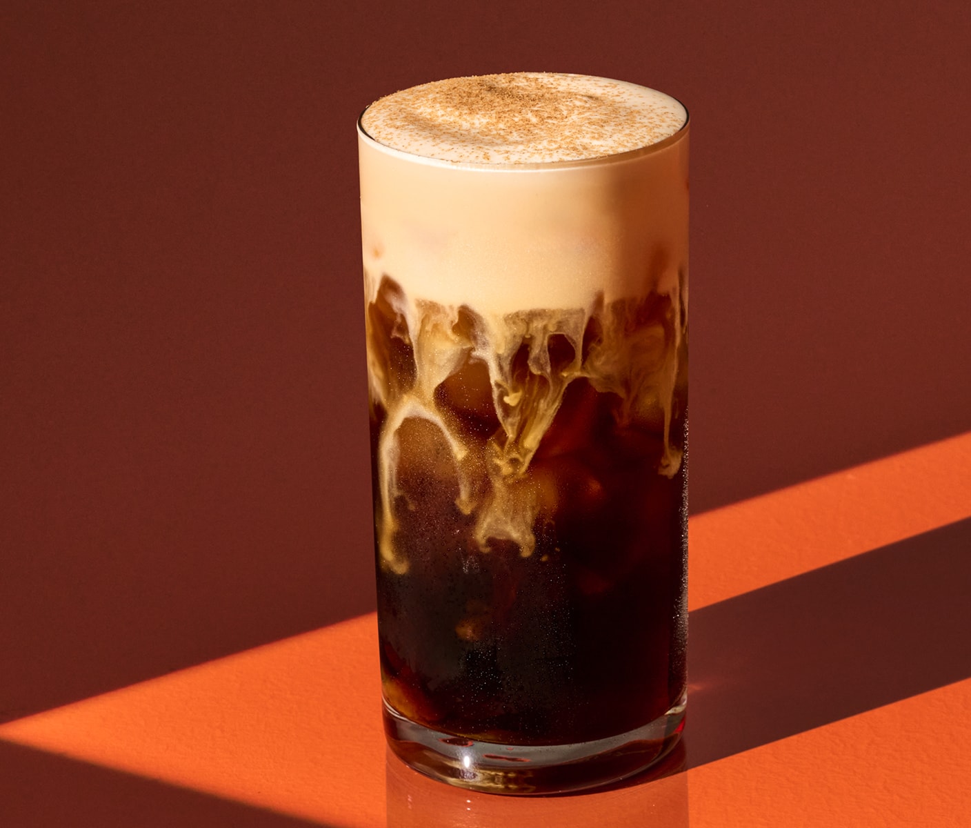 An iced coffee drink with a thick layer of pumpkin cream cold foam.