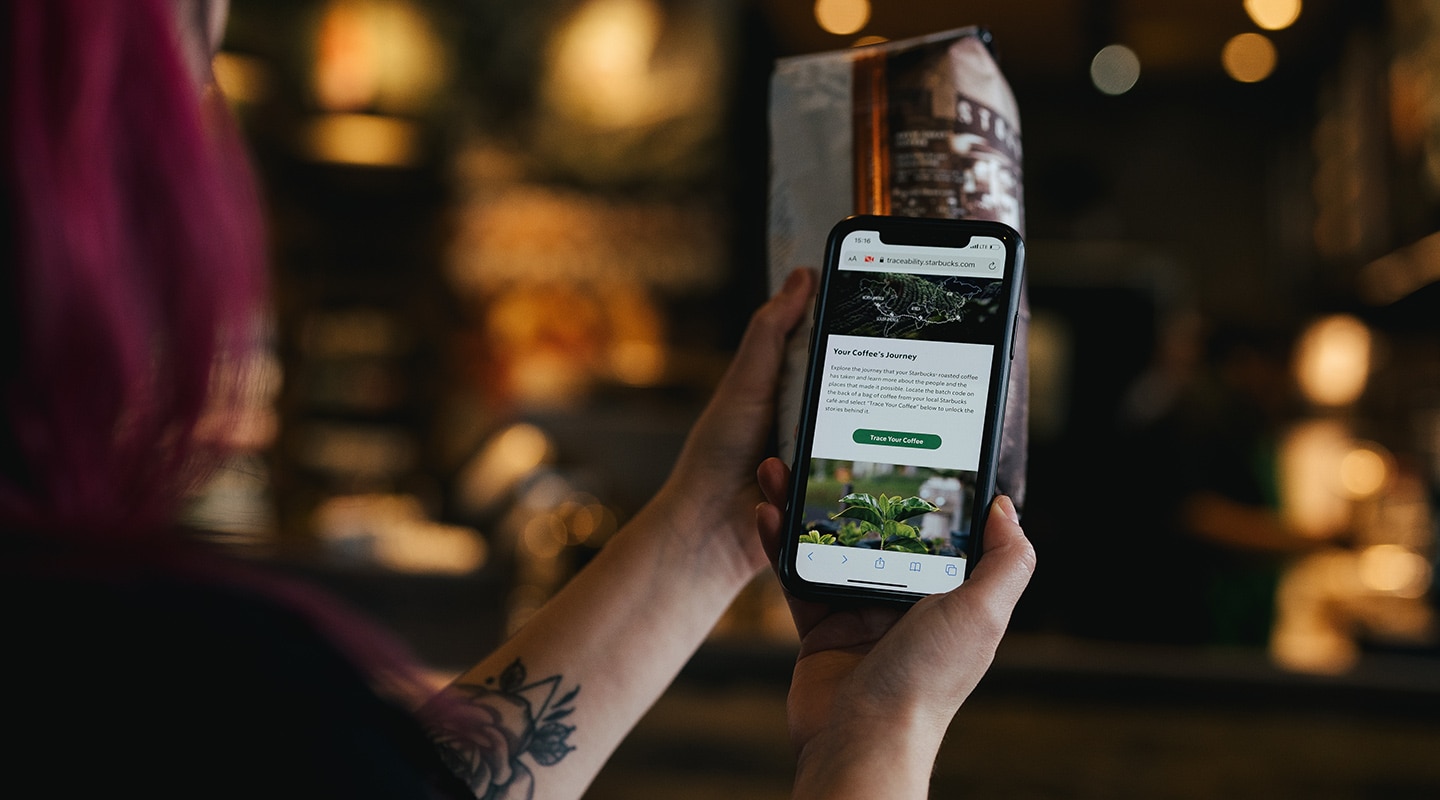 A person holding their phone using the traceability tool, scanning the code on a bag of coffee.