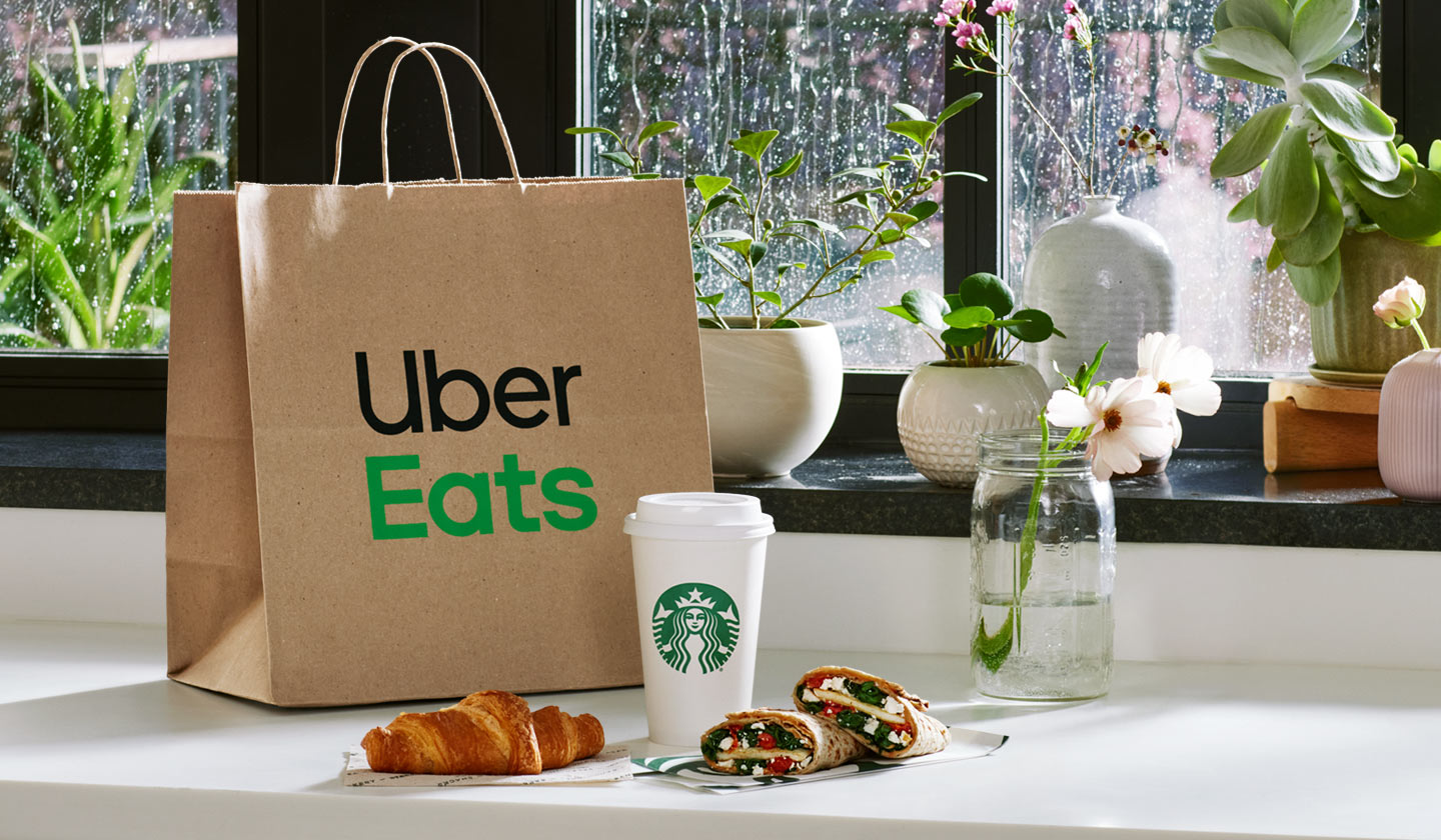 An Uber Eats delivery bag and assortment of Starbucks coffee and bakery items on a counter