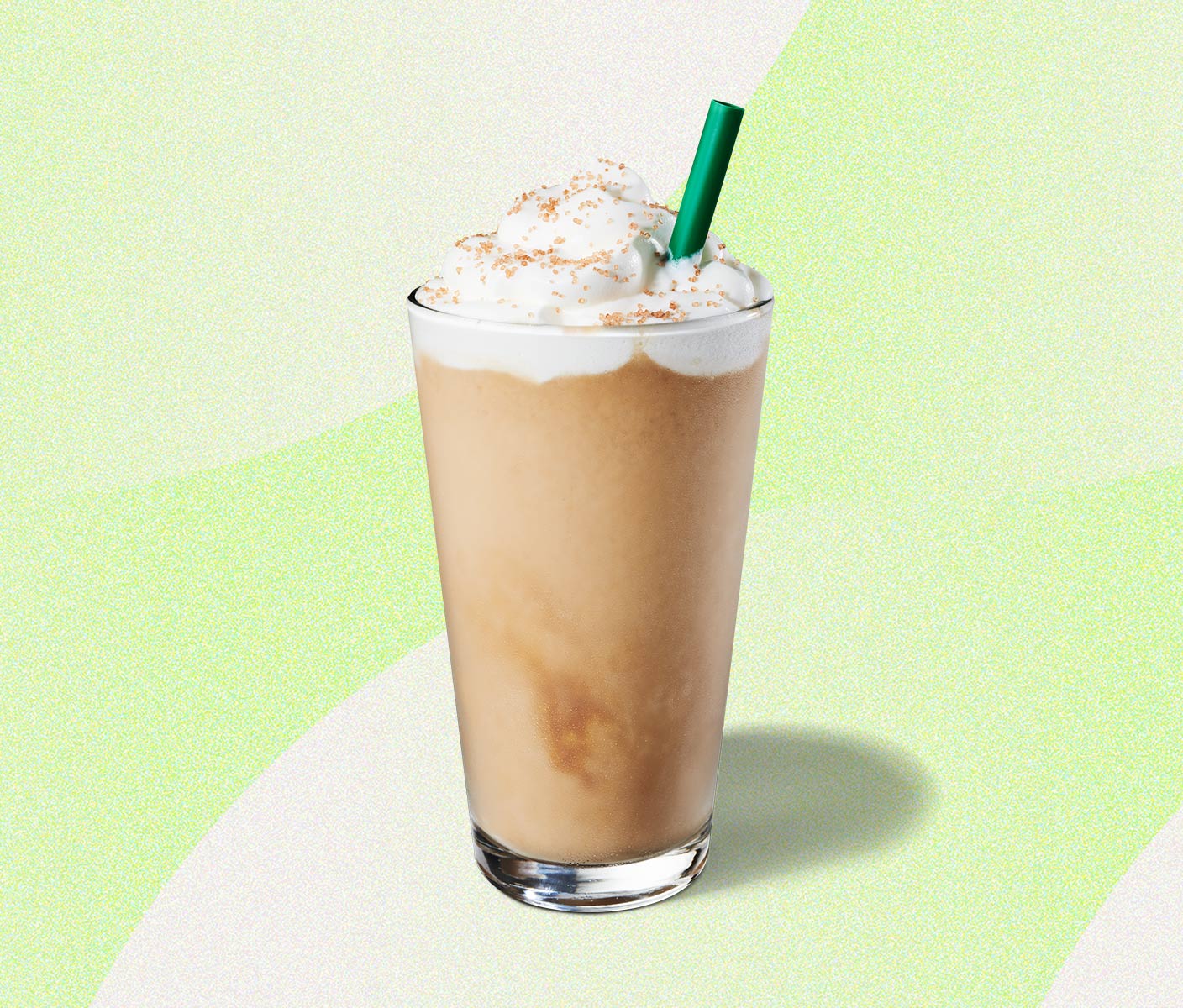 Blended coffee beverage with whipped cream and a green straw in a tall glass.