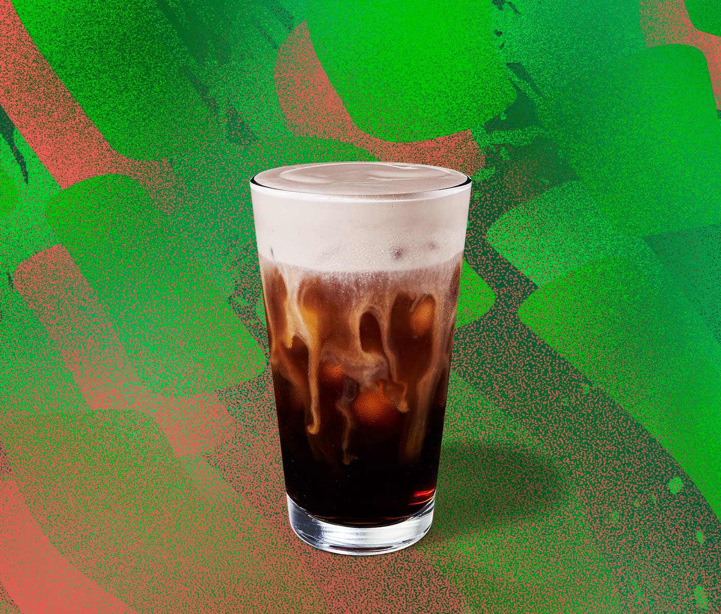 Iced coffee drink topped with foam in a tall glass.