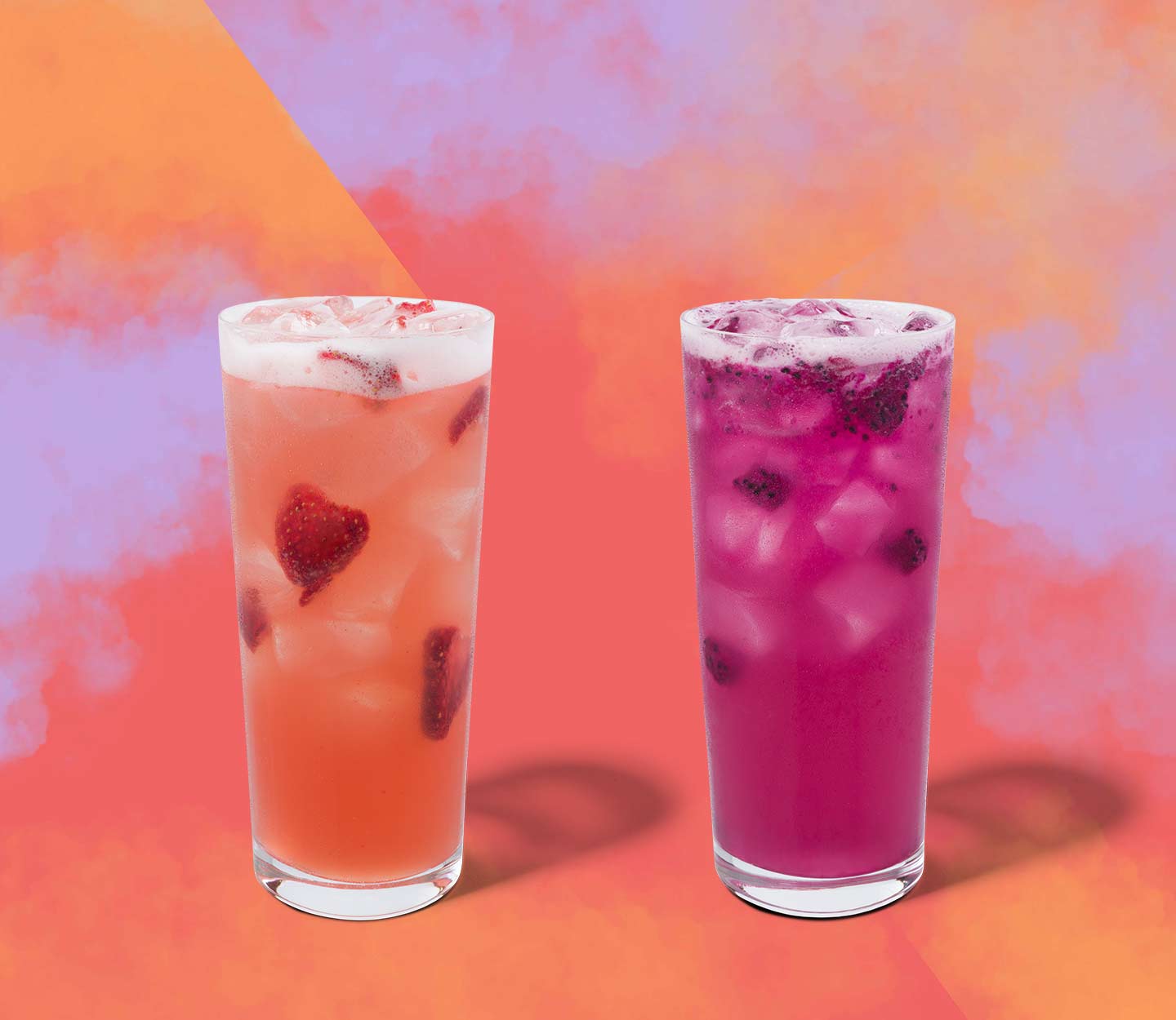 Two colourful iced drinks with fruit inclusions in tall glasses.