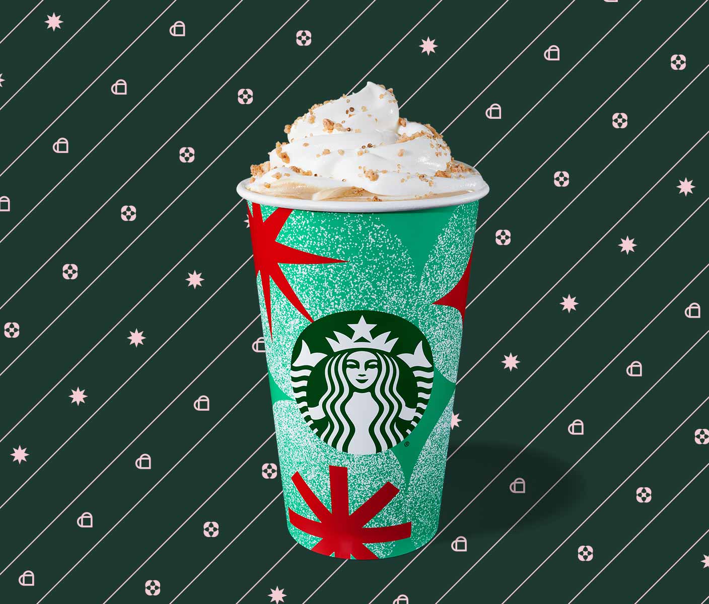 Hot espresso drink with whipped cream in a to-go cup with red stars on a green background.