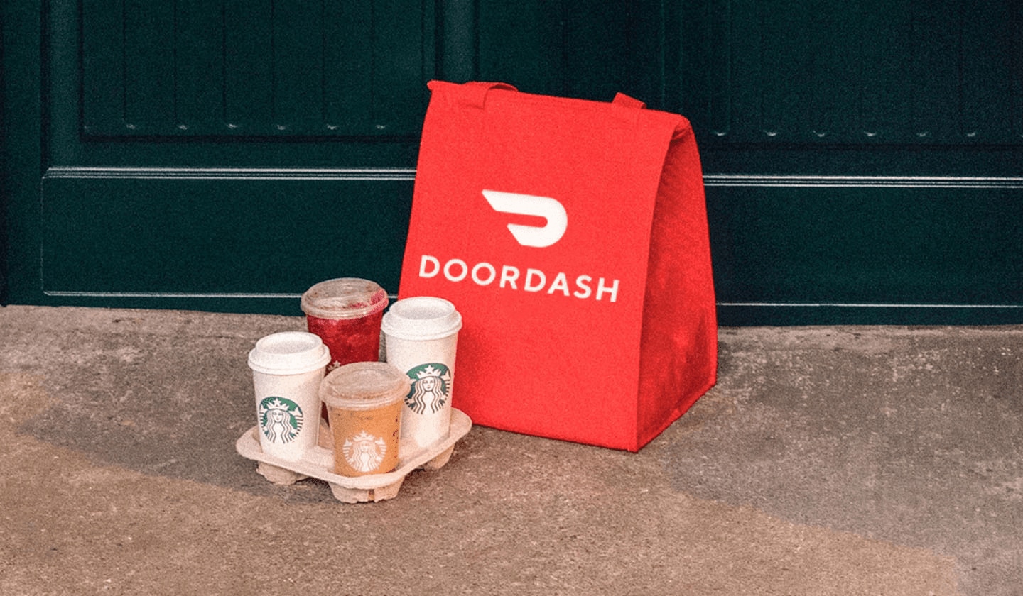 A red DoorDash bag sits next to a Starbucks drink carrier holding four beverages.