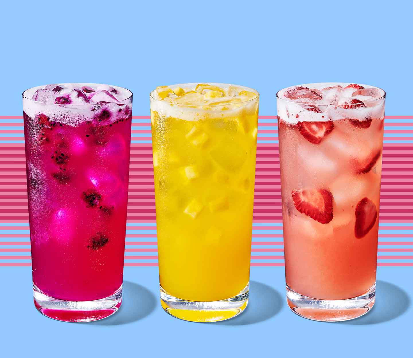 Three tall glasses sit side by side and are filled with fruity drinks that show fruit inclusions.