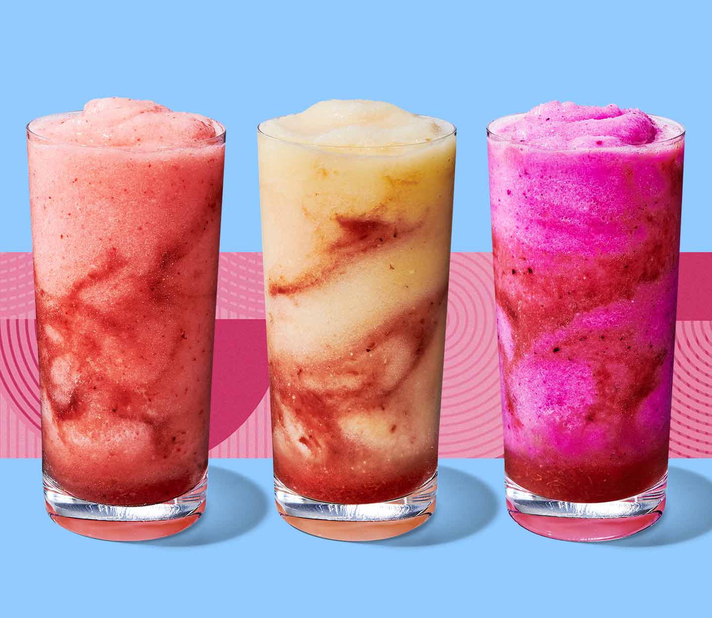 Three frozen blended drinks with colourful swirls in tall glasses.