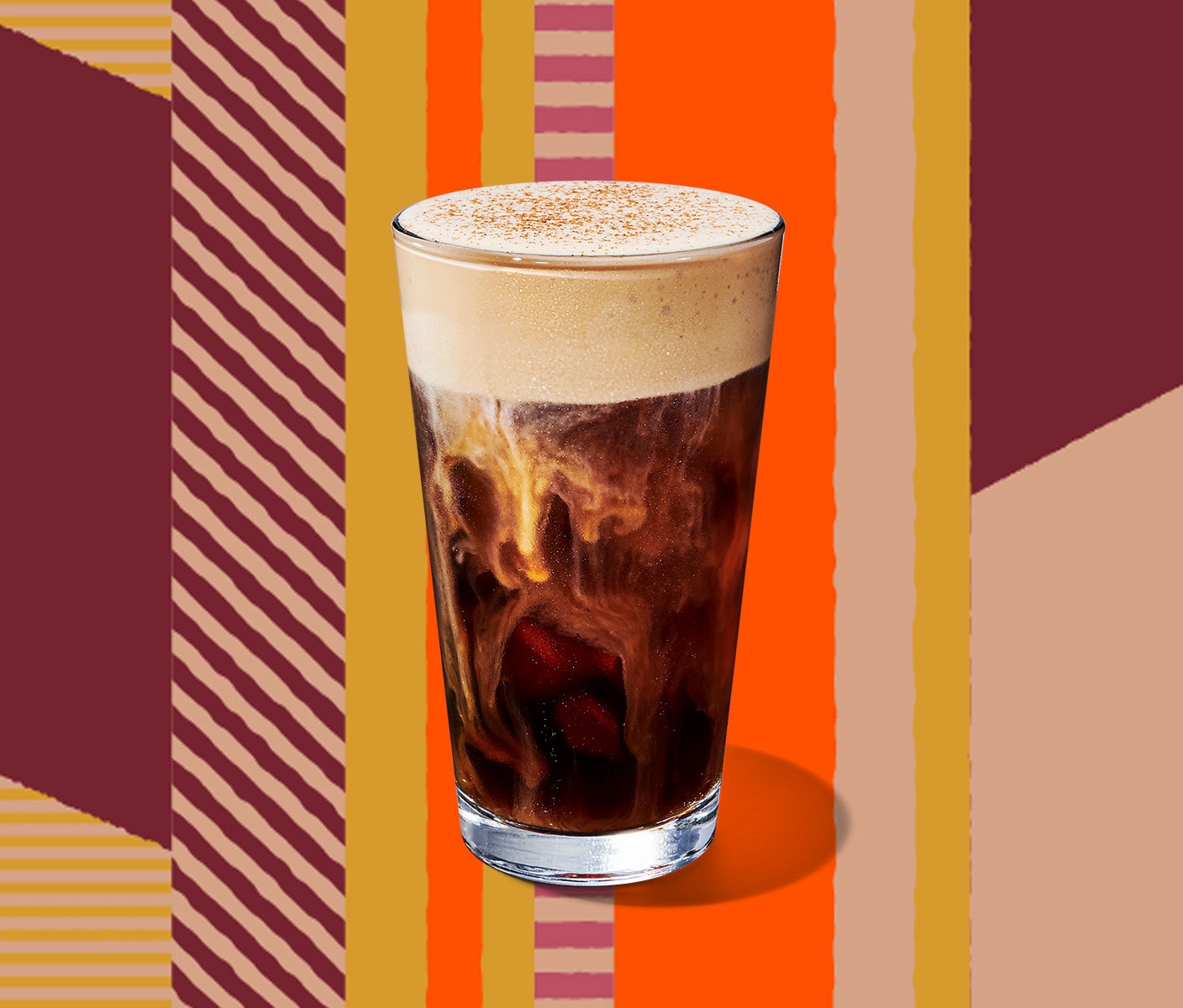 A cold coffee with a thick, foamy top in a tall glass.