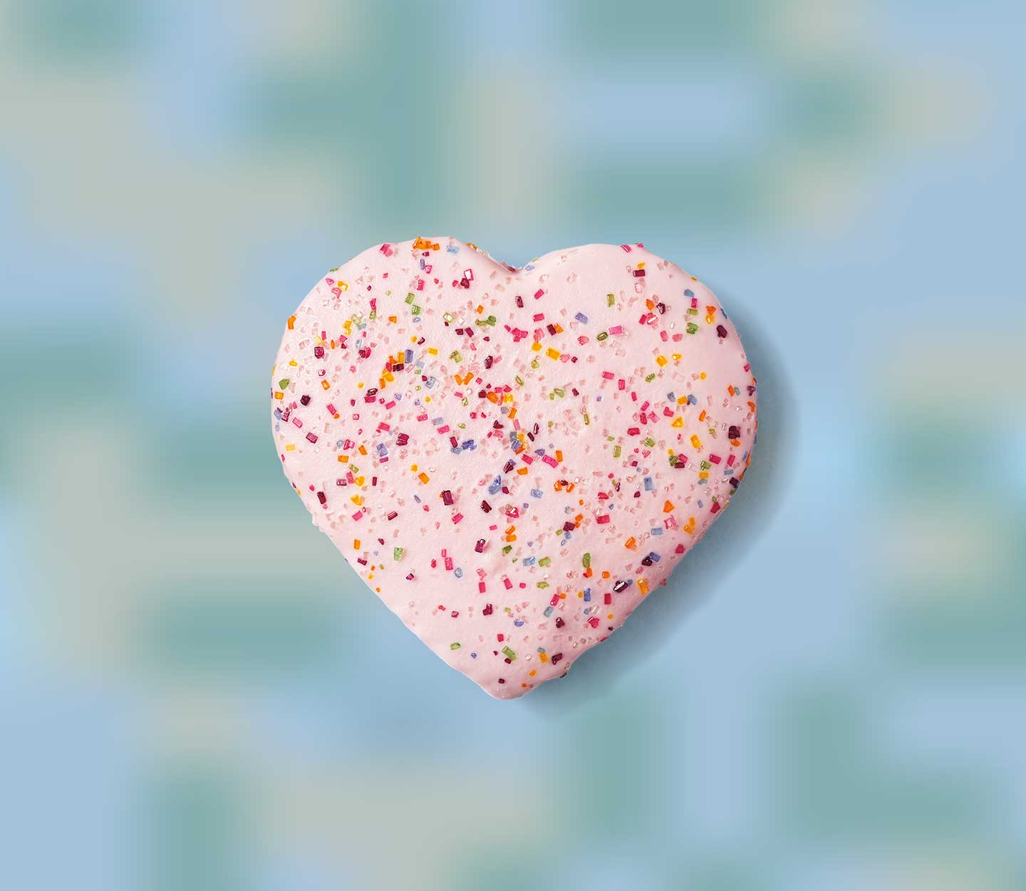 A heart-shaped cookie covered in colourful sprinkles.