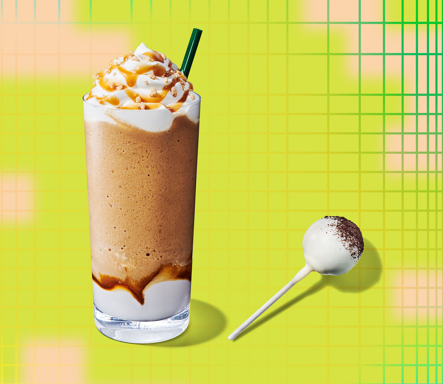 A chocolaty blended drink with whipped cream and a straw next to a white-frosted cake pop laying on its side.
