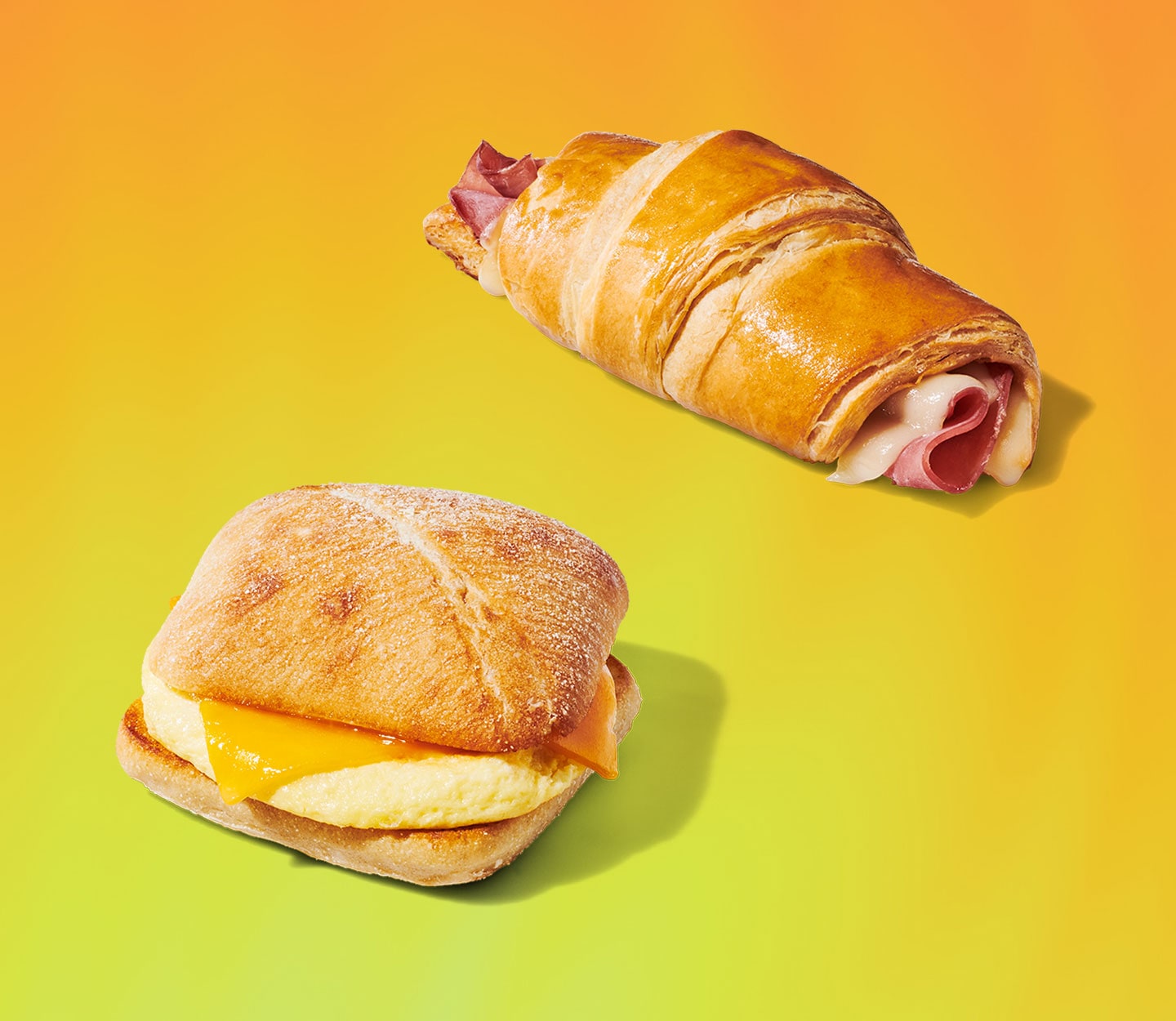 A hot breakfast sandwich and a croissant stuffed with ham and swiss cheese.