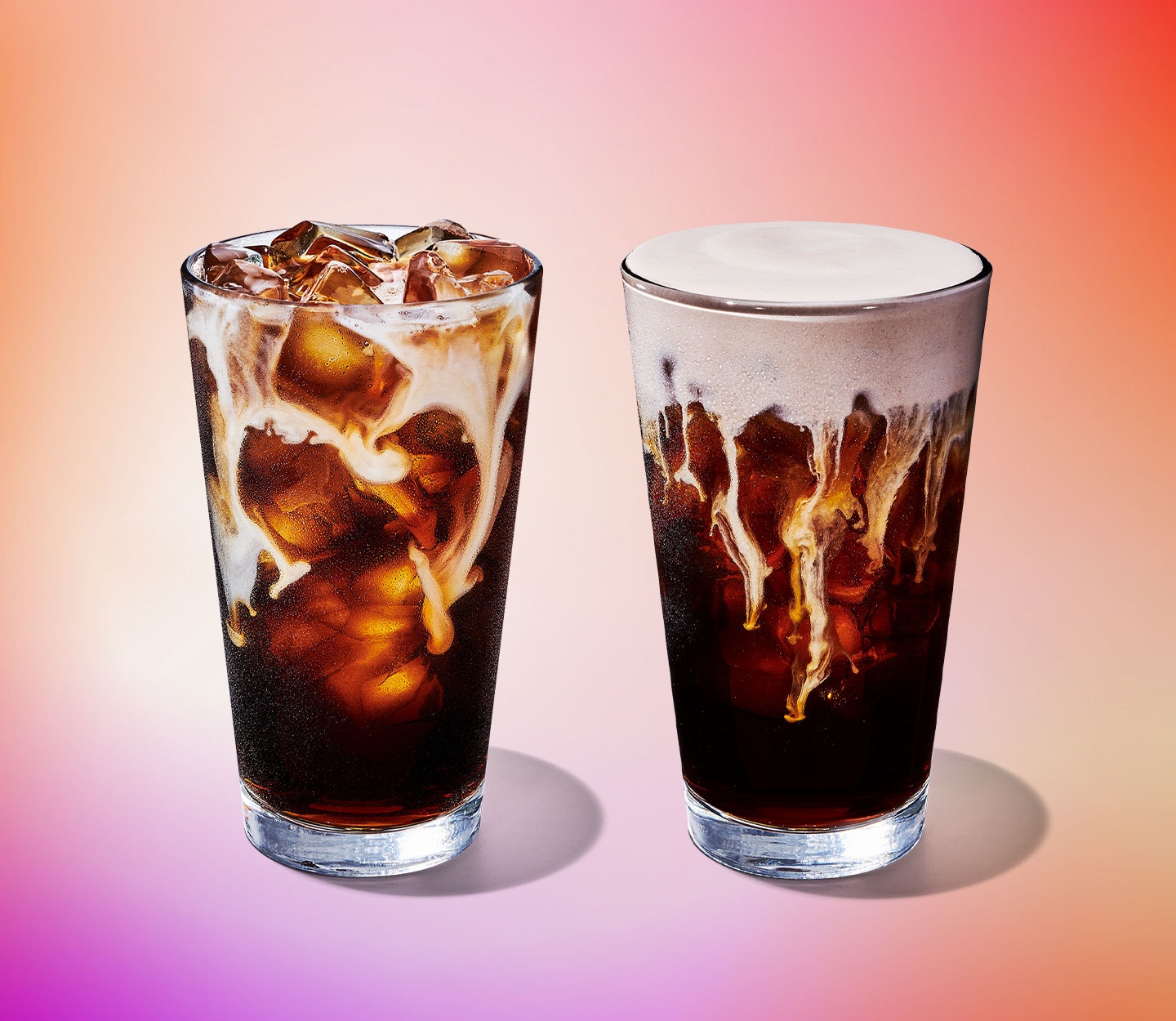 Two iced coffee drinks with creamy, foamy toppings swirling throughout the glass.