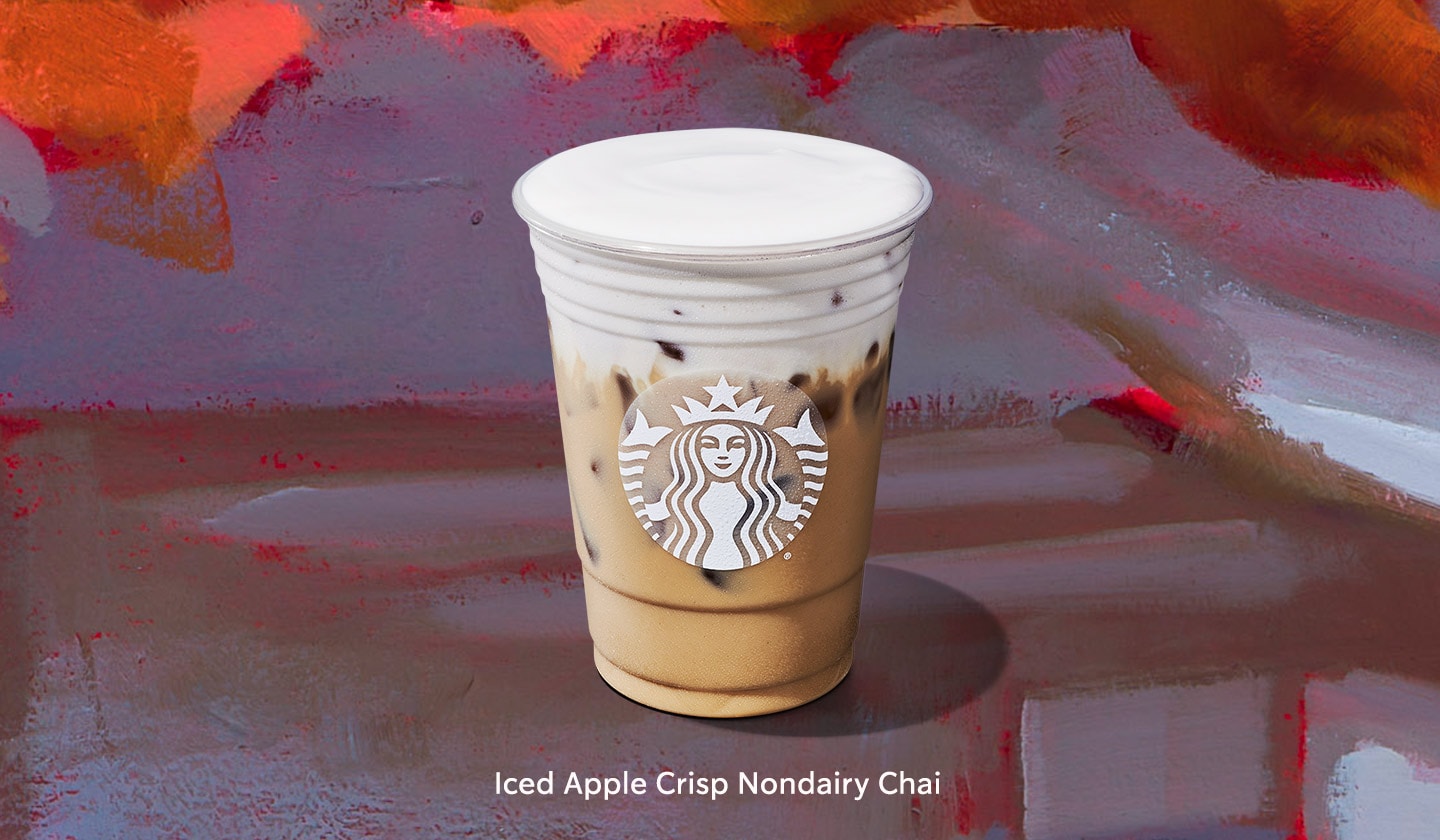 An Iced Apple Crisp Nondairy Chai with its light beige coffee base beneath a layer of white foam