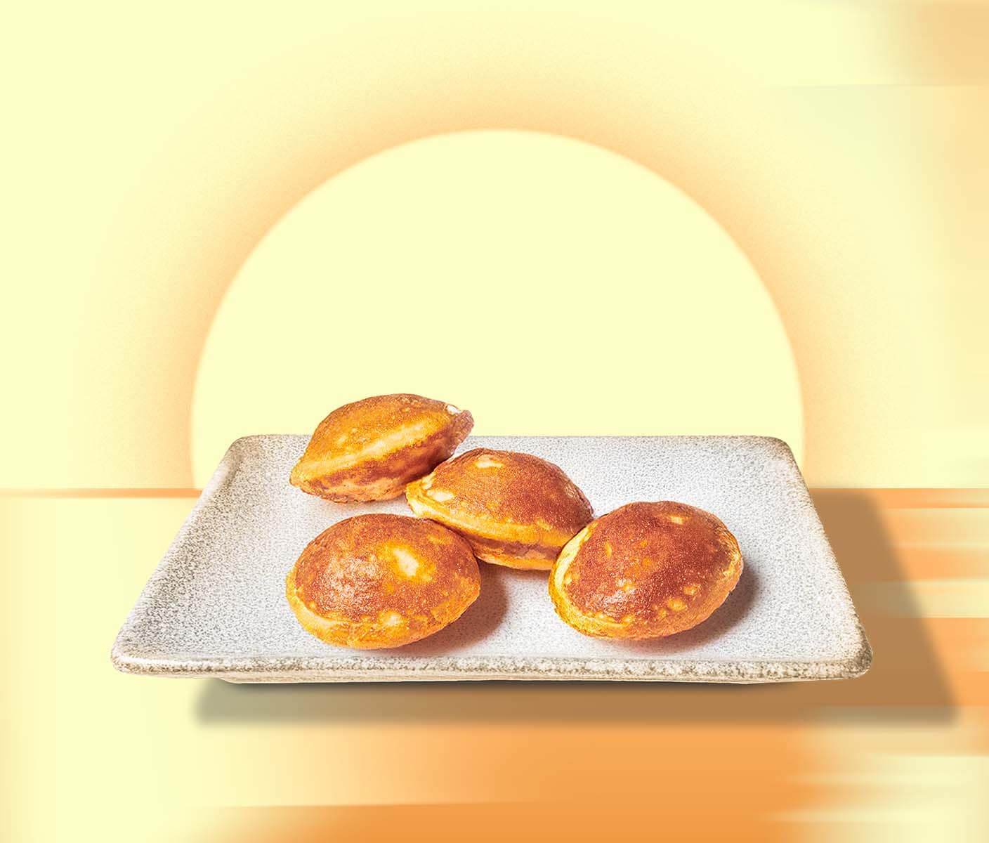 A stoneware plate with four golden brown mini pancakes sitting against a warm yellow background featuring a rising sun.