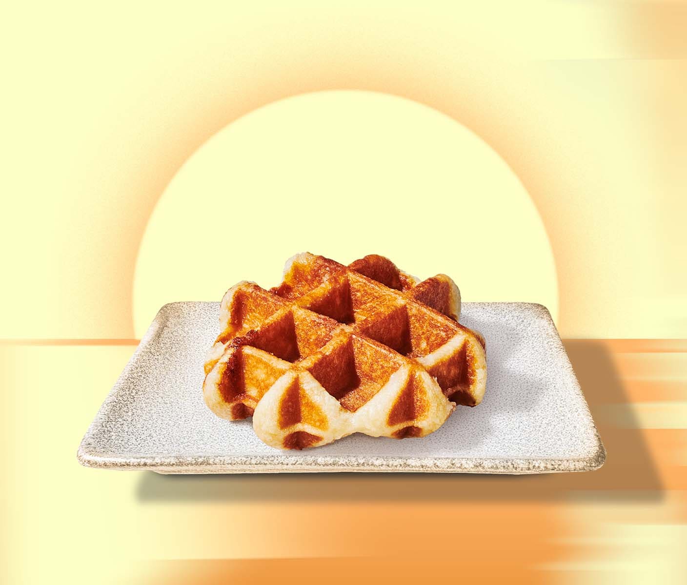 A golden brown waffle on a stoneware plate against a warm yellow background featuring a rising sun.